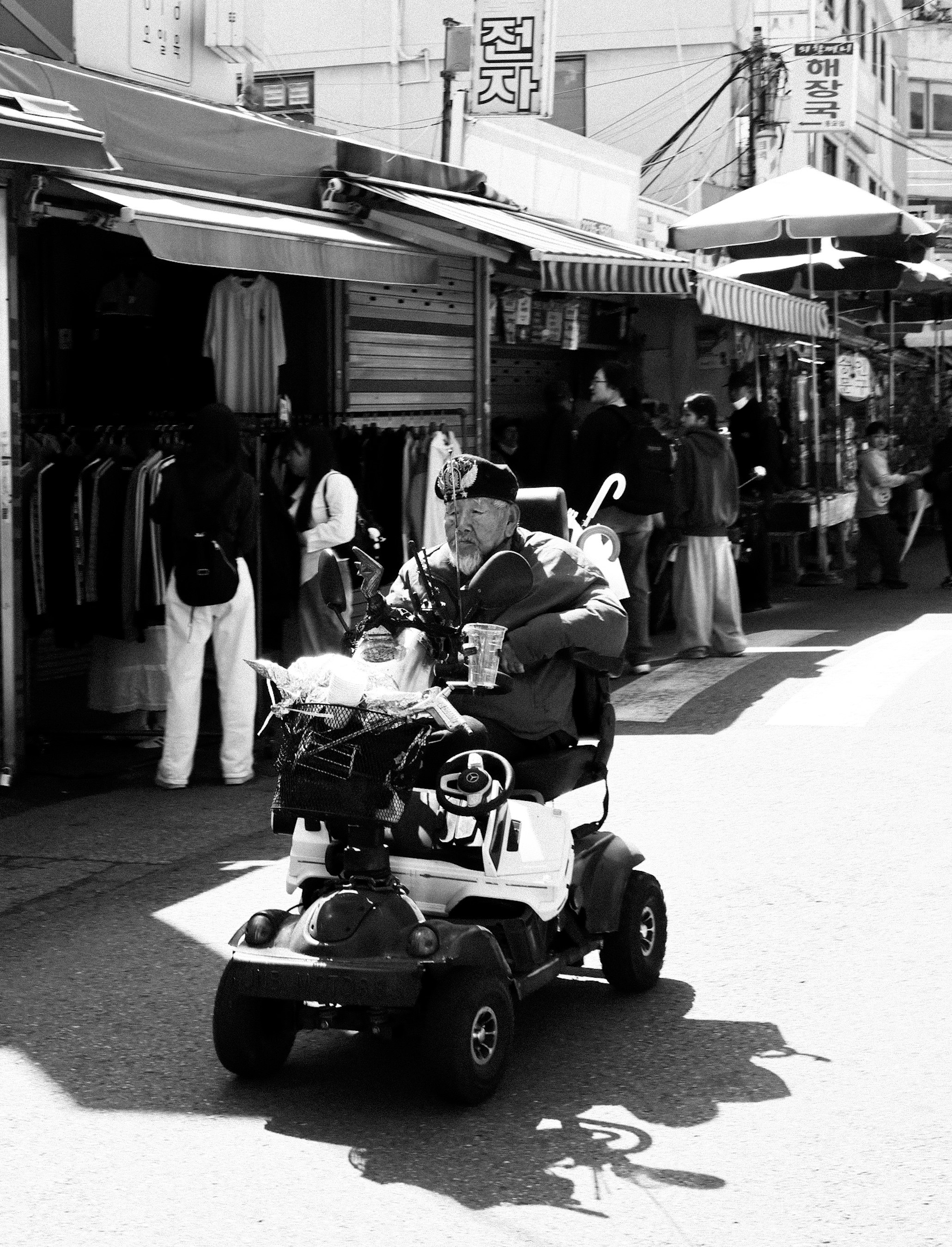 路地の商店街でバイクに乗る男性と買い物客の行き交い