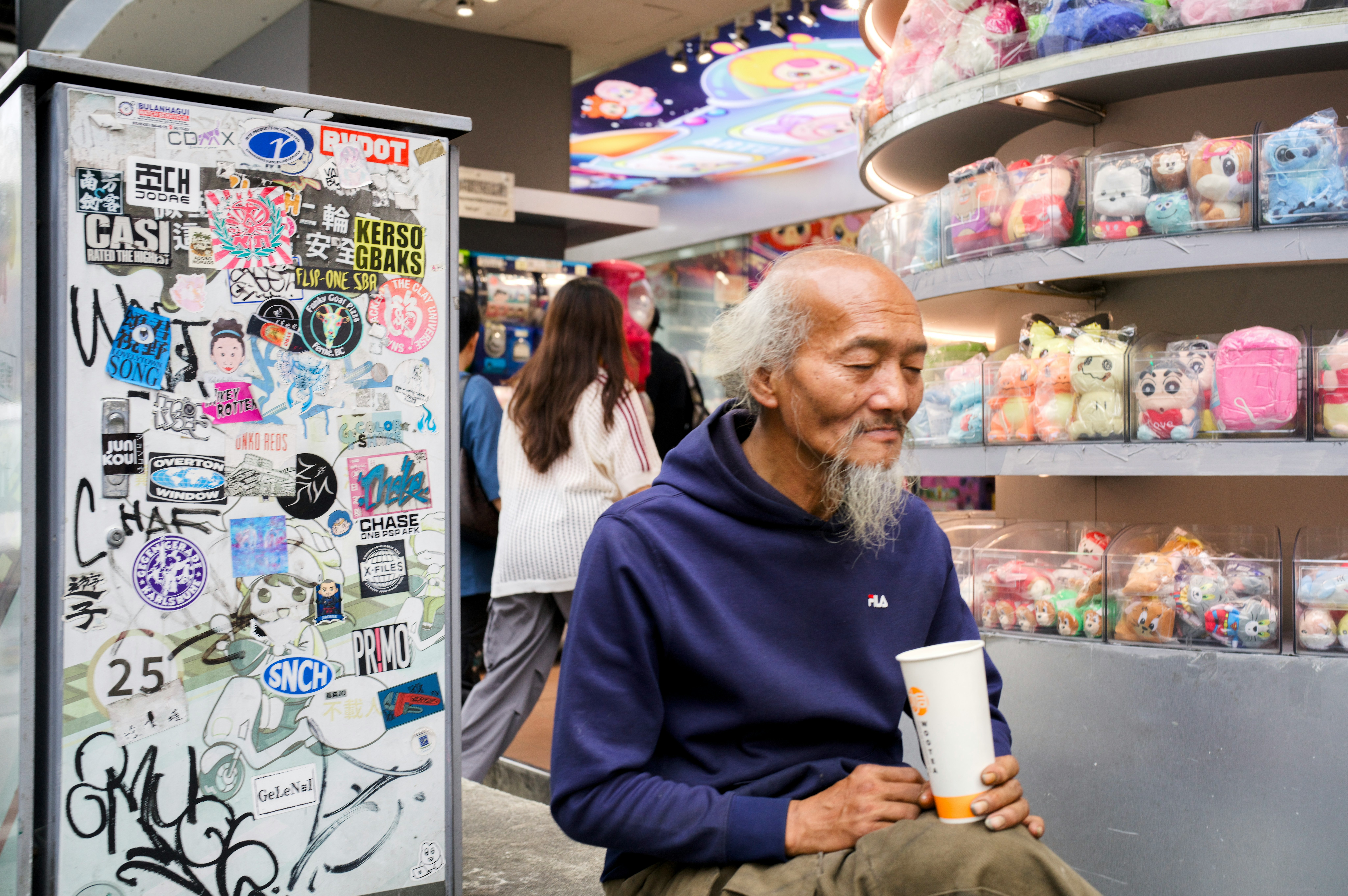 店内でカップを手にする男性とぬいぐるみの棚