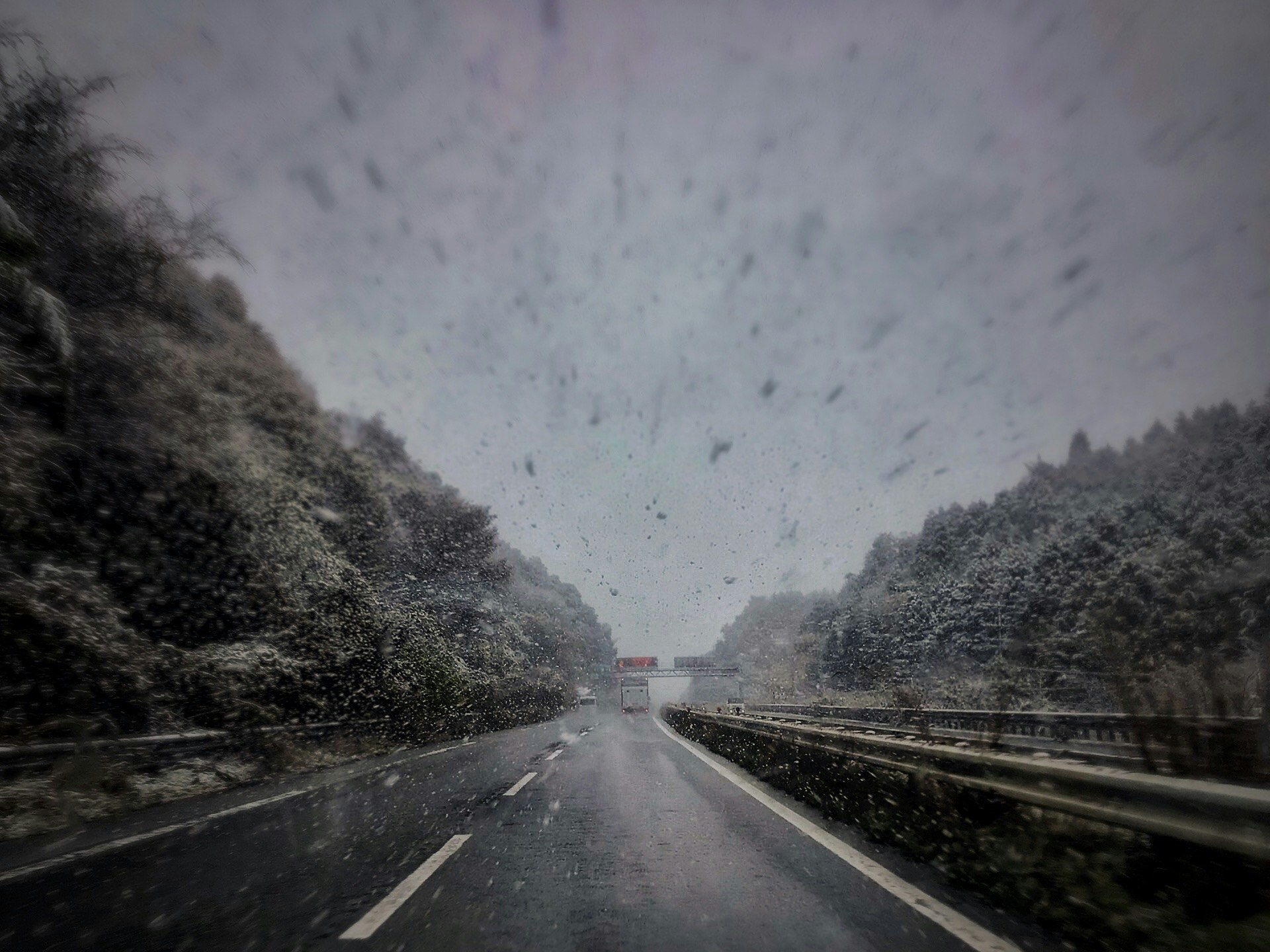 吹雪の国道を走行する車のある雪景色