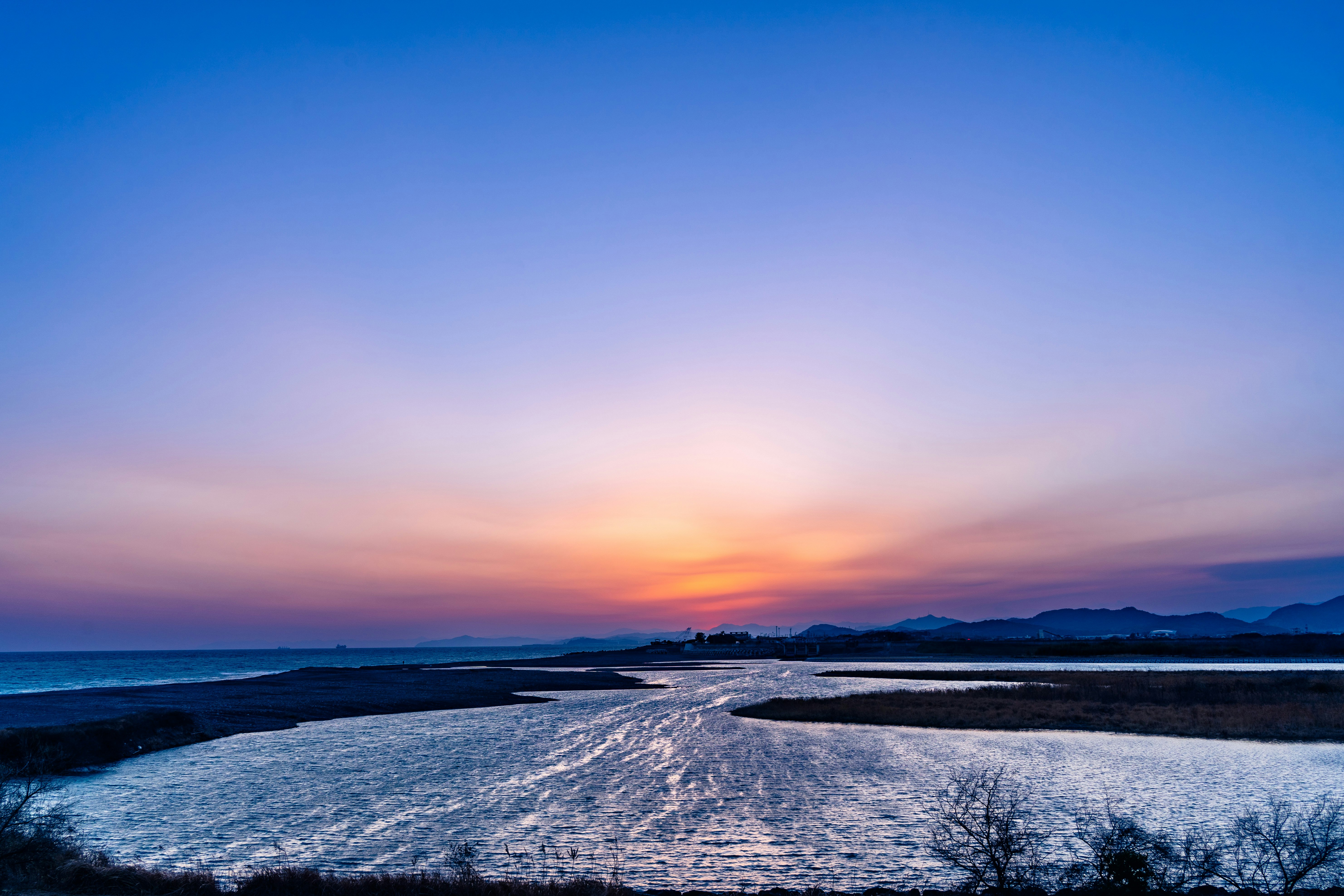 夕焼けの海岸線と波が続く風景
