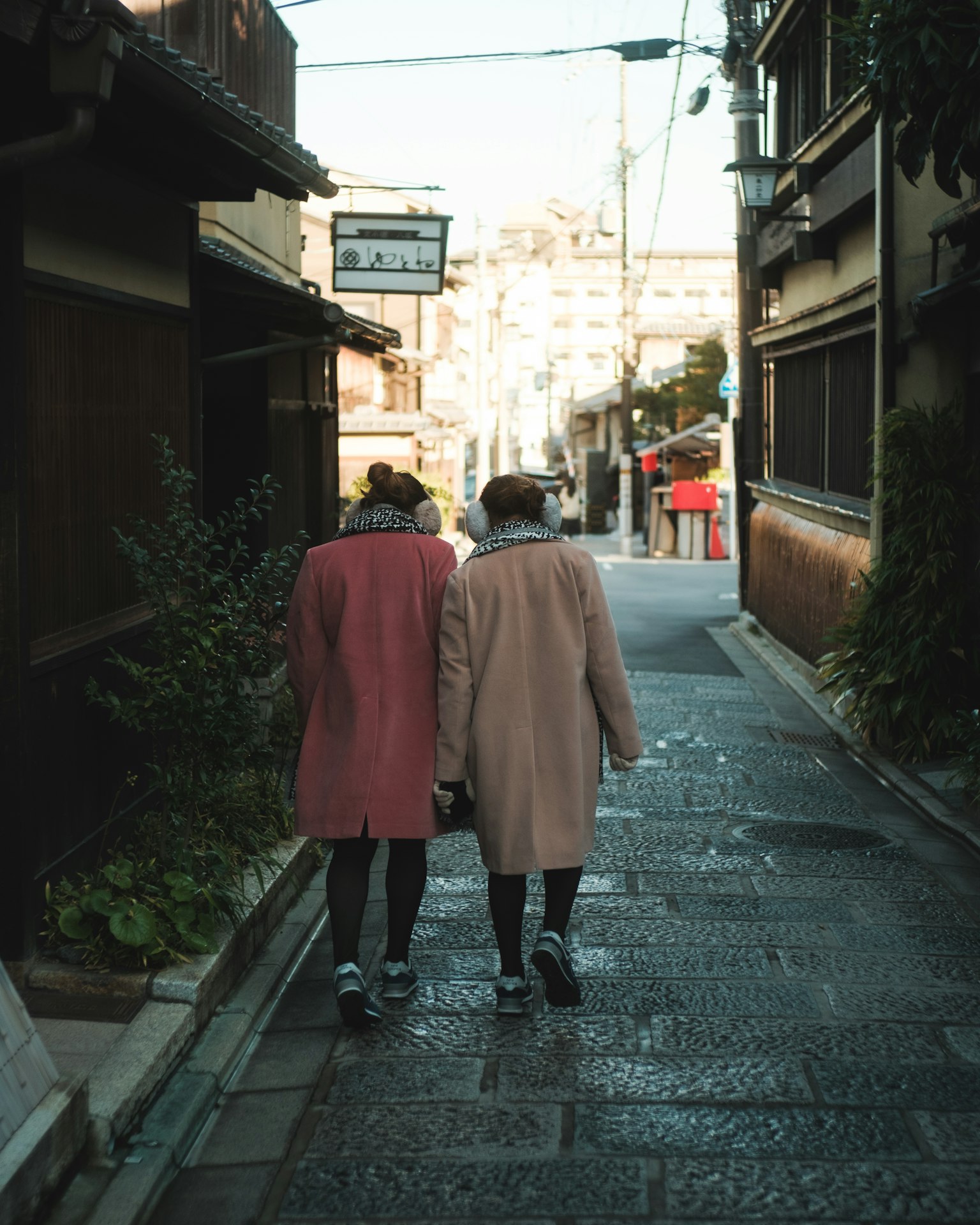 Due donne che camminano in una strada stretta indossando cappotti rosa