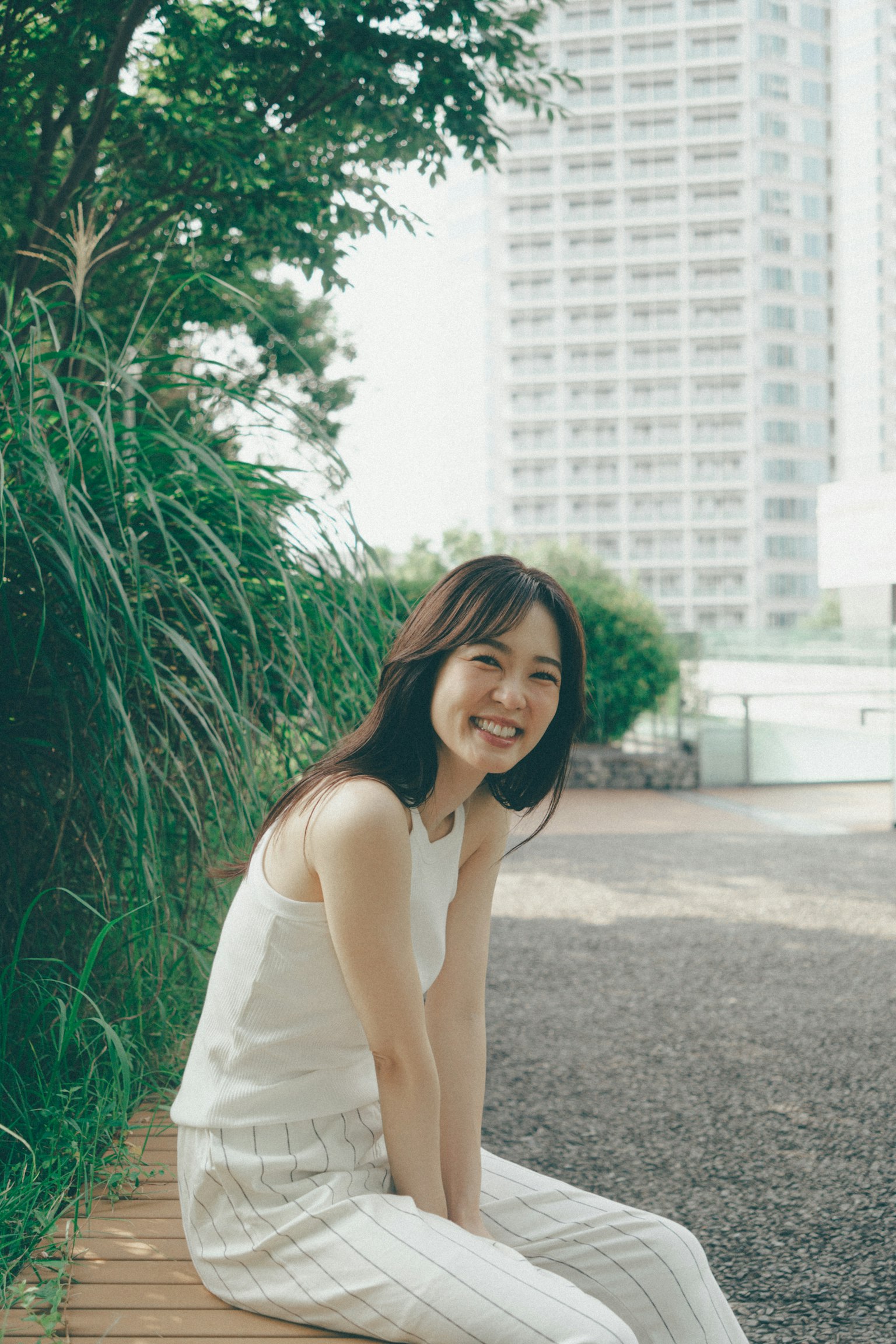 Una mujer sonriente sentada en un parque rodeada de vegetación