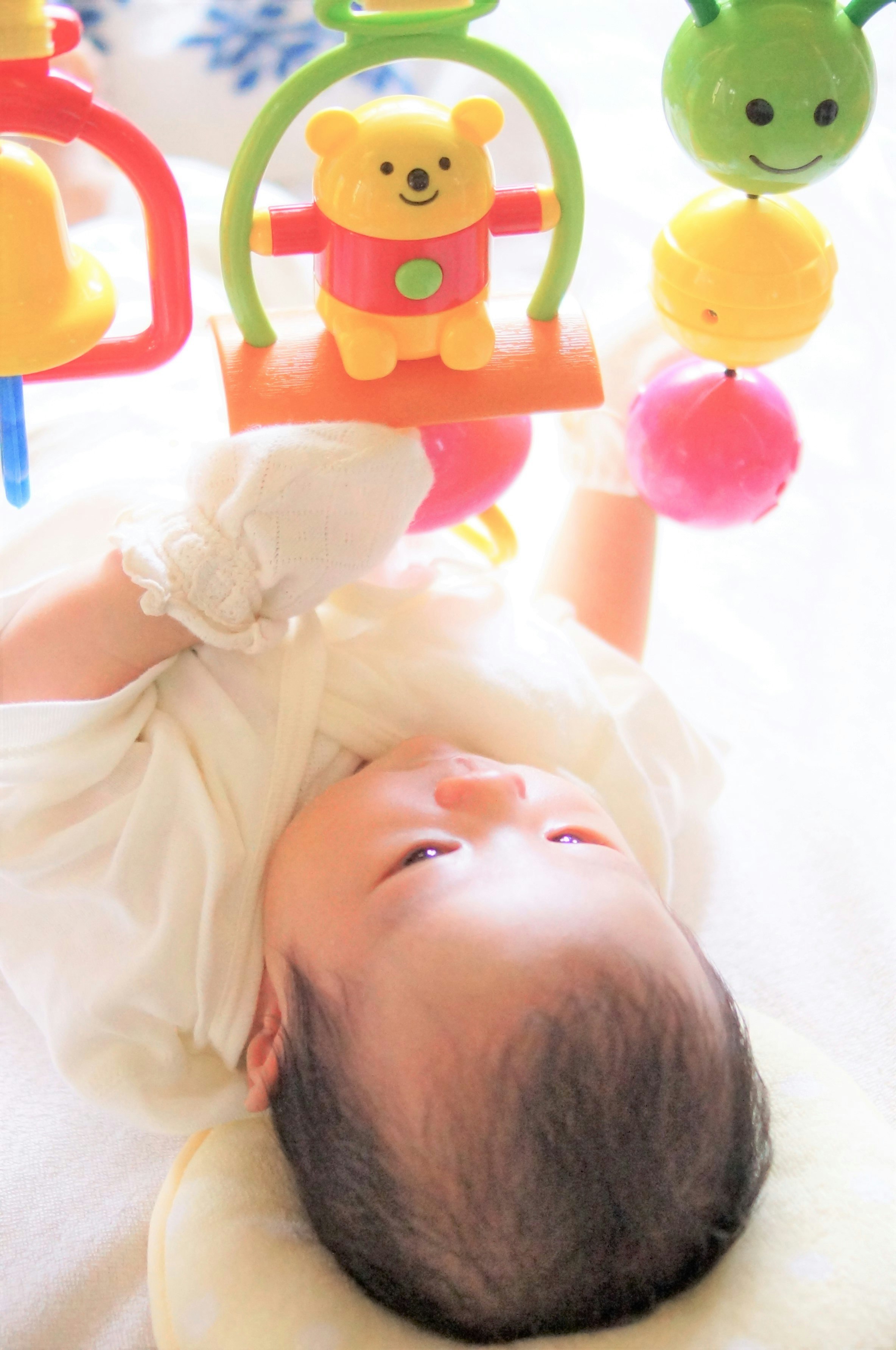 baby lying on a bed with cute toys in a bright indoor room