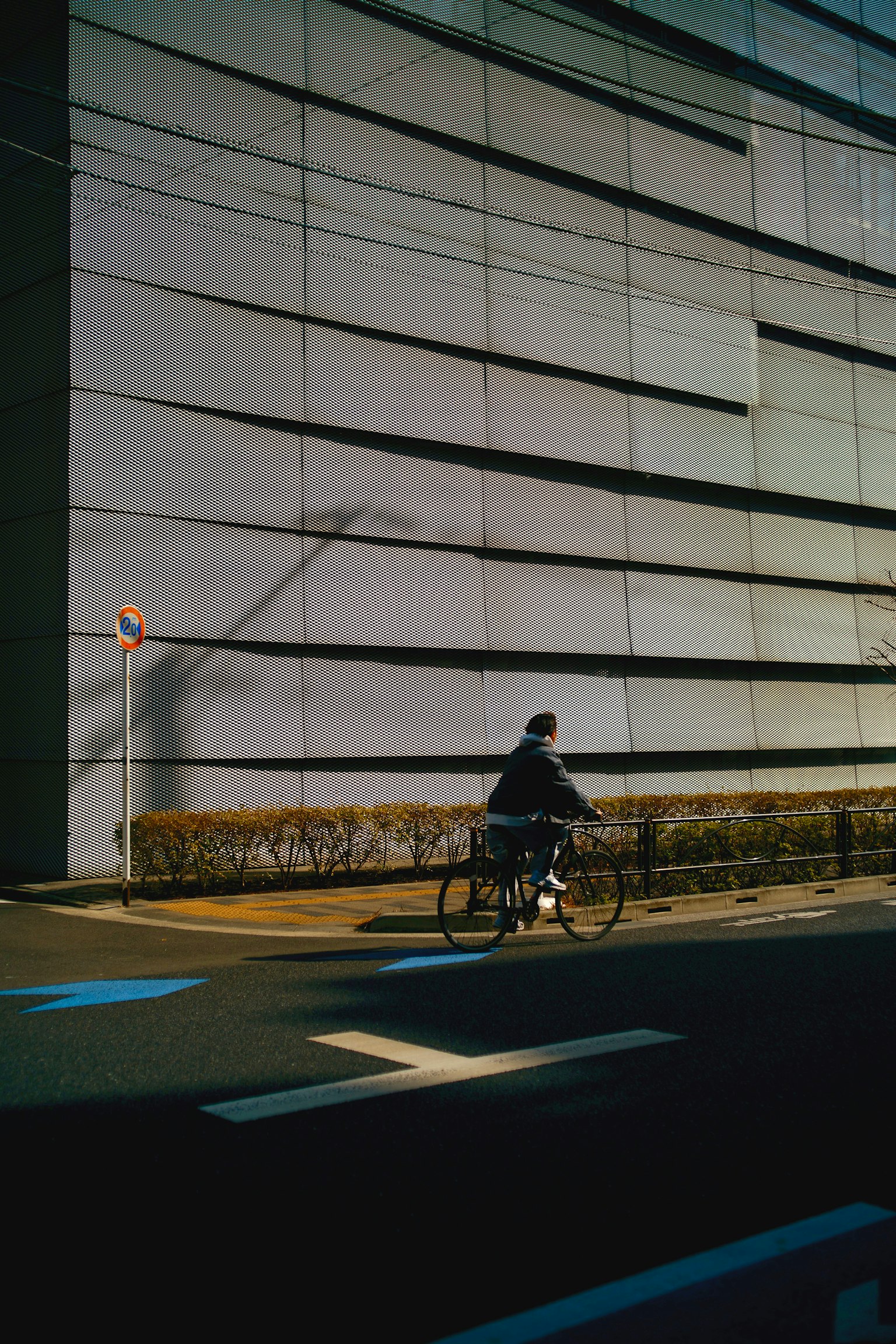 Una persona montando en bicicleta junto a la pared de un edificio moderno
