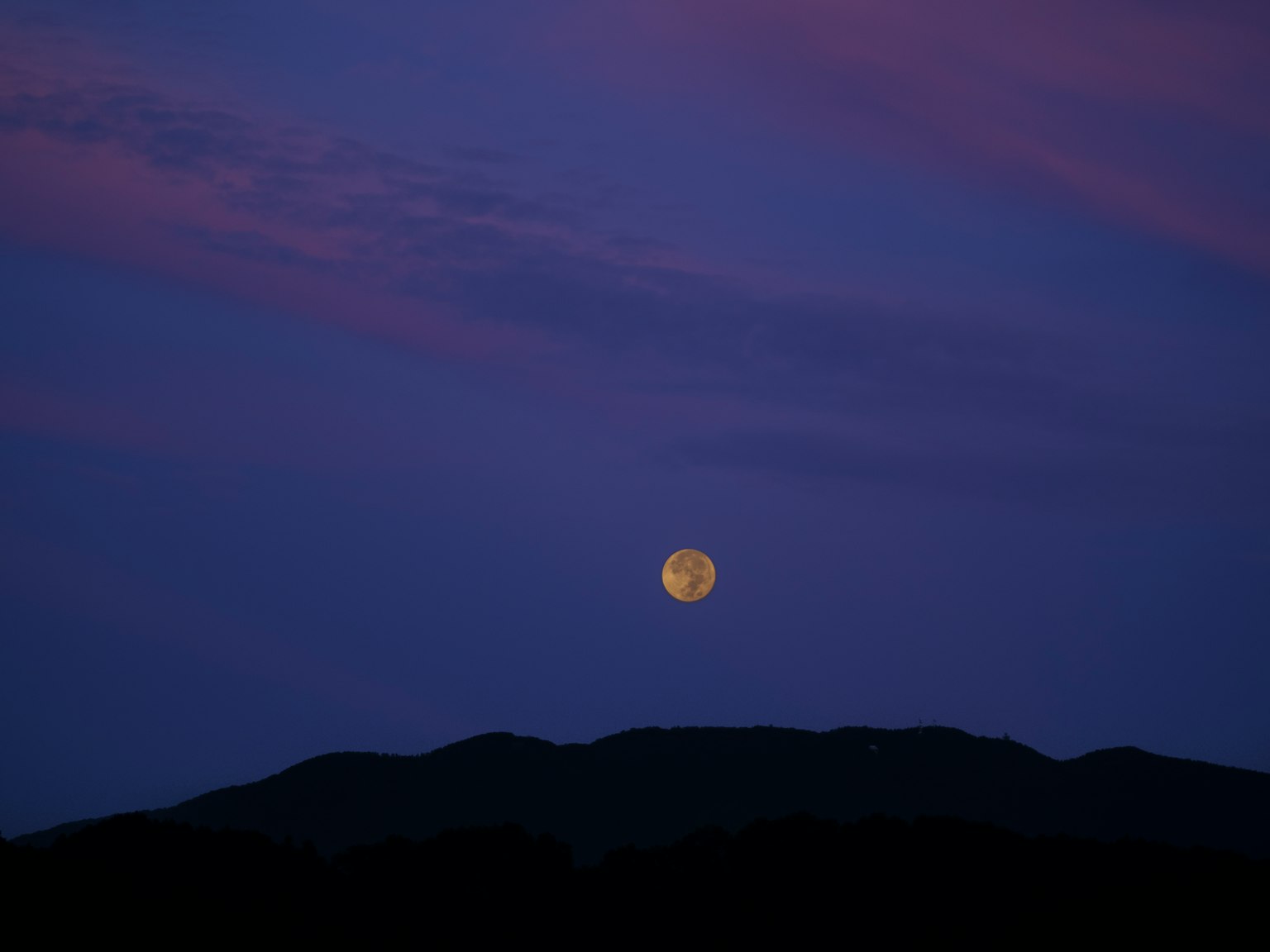 Luna piena sopra le montagne con cielo viola