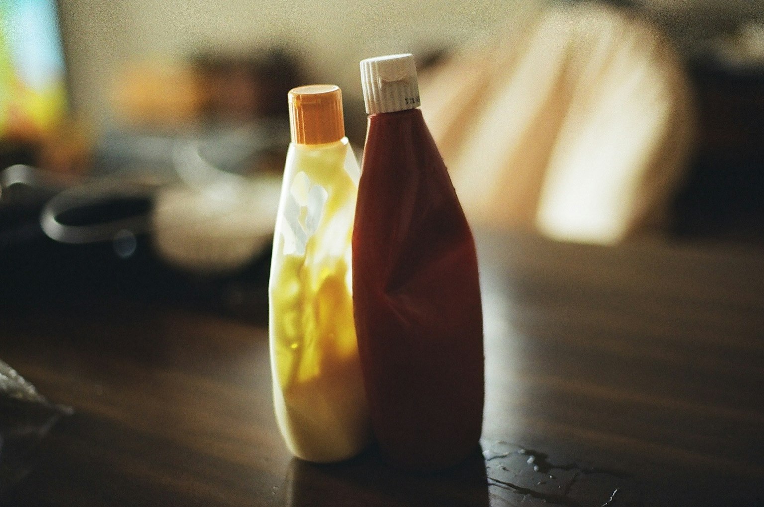 Bottiglie di senape gialla e ketchup rosso su un tavolo