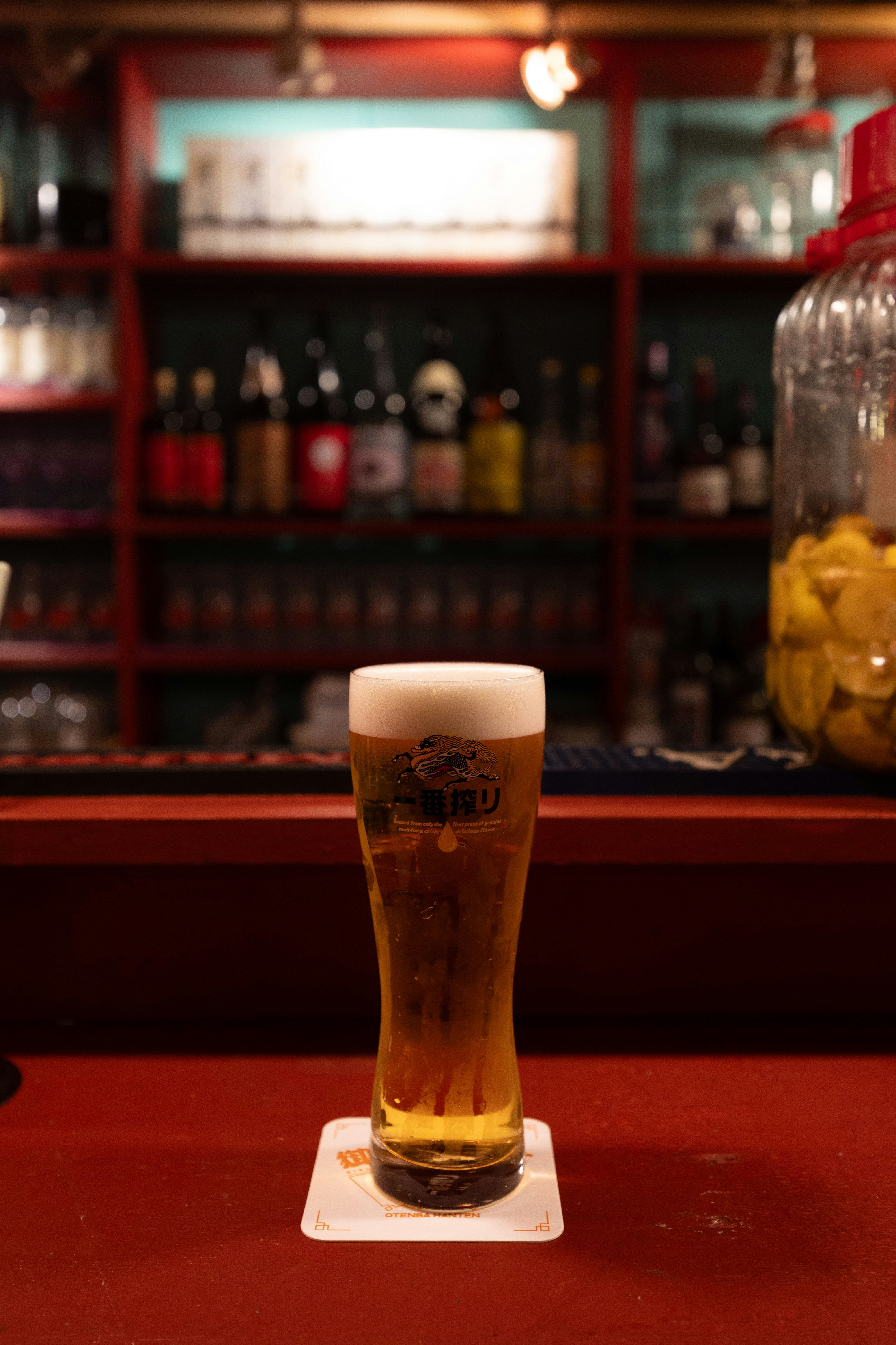 赤いバーのカウンターに置かれたビールグラスの画像