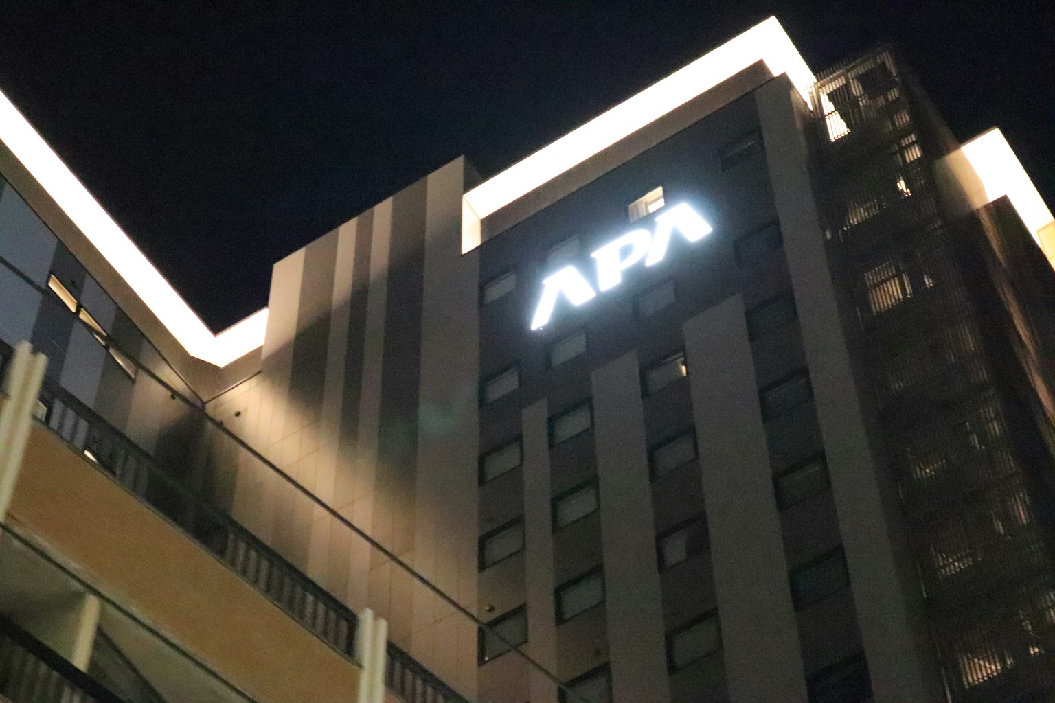 ทิวทัศน์ยามค่ำคืนของโรงแรม APA พร้อมป้ายที่สว่าง