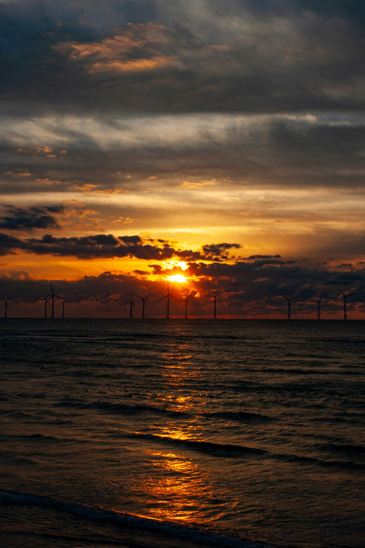 海の夕日と風力発電のタービンが見える美しい景色