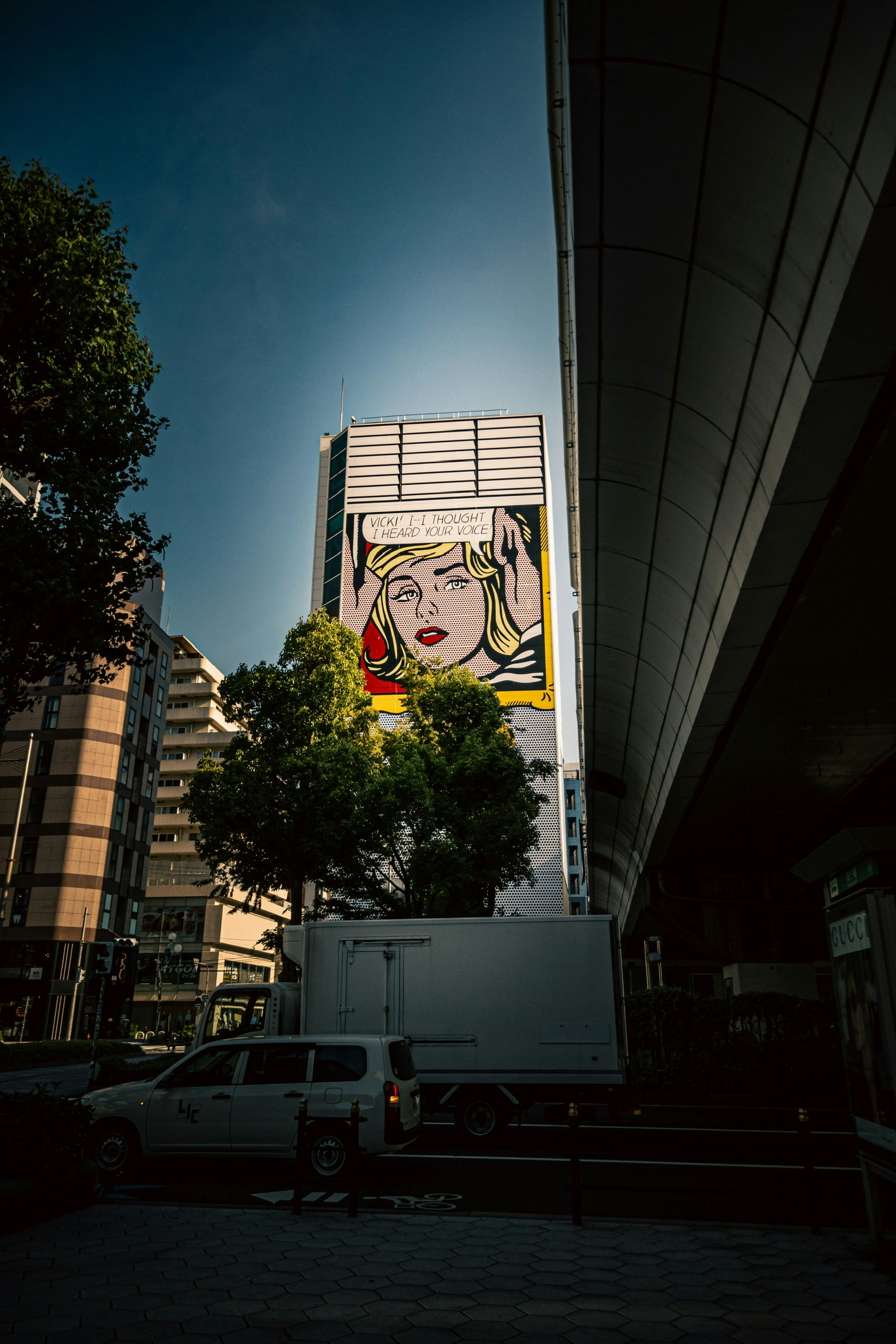 Pop-Art-Wandgemälde eines Frauenkopfes an einem Stadtgebäude mit blauem Himmel