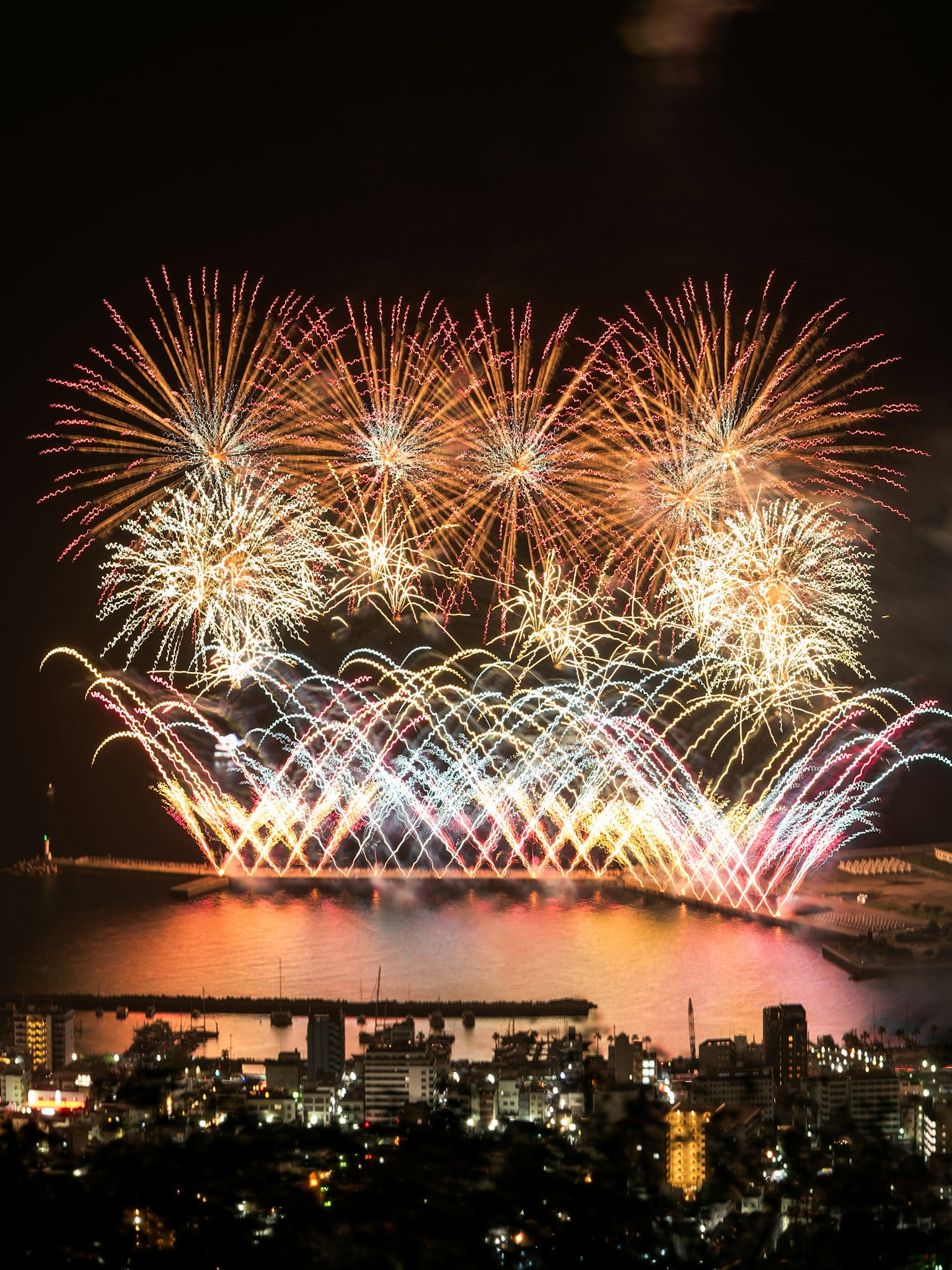 Fuegos artificiales vibrantes iluminando el cielo nocturno sobre el mar