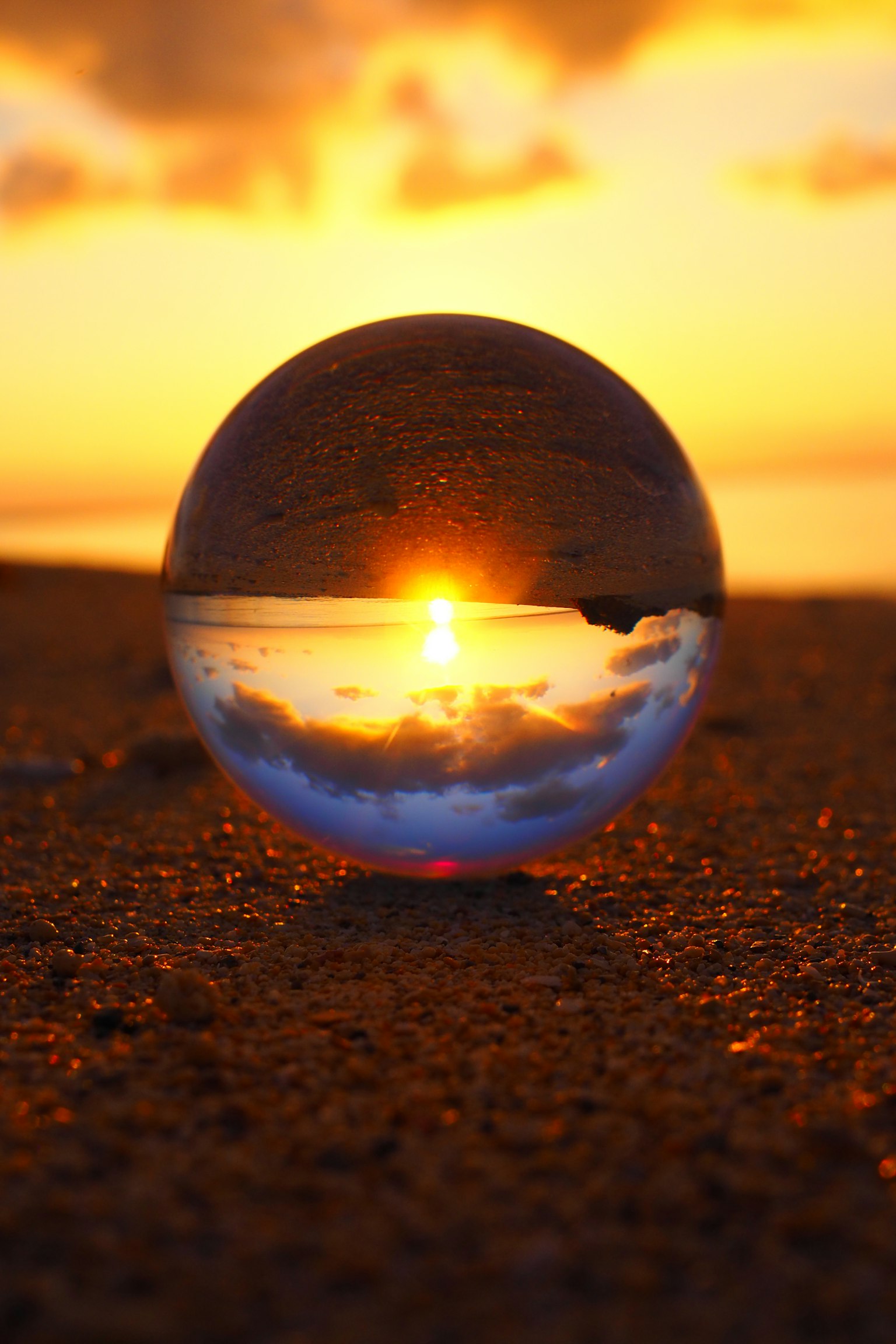 Une boule en cristal reflétant un coucher de soleil sur l'océan