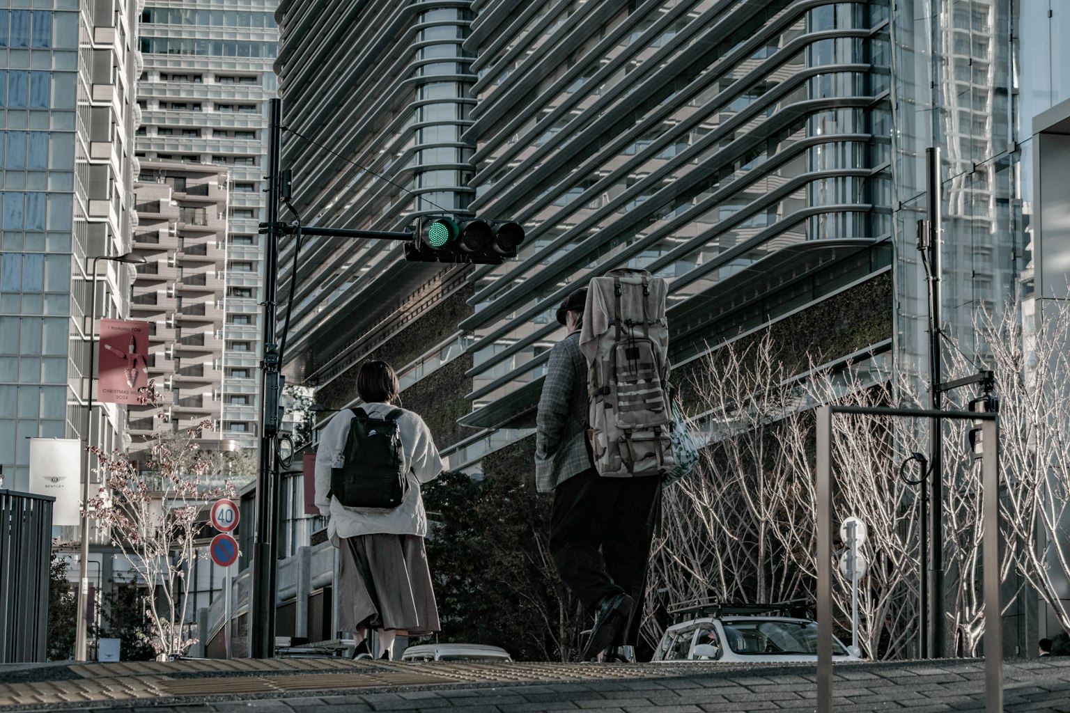 两个人在城市环境中走过，绿灯亮着