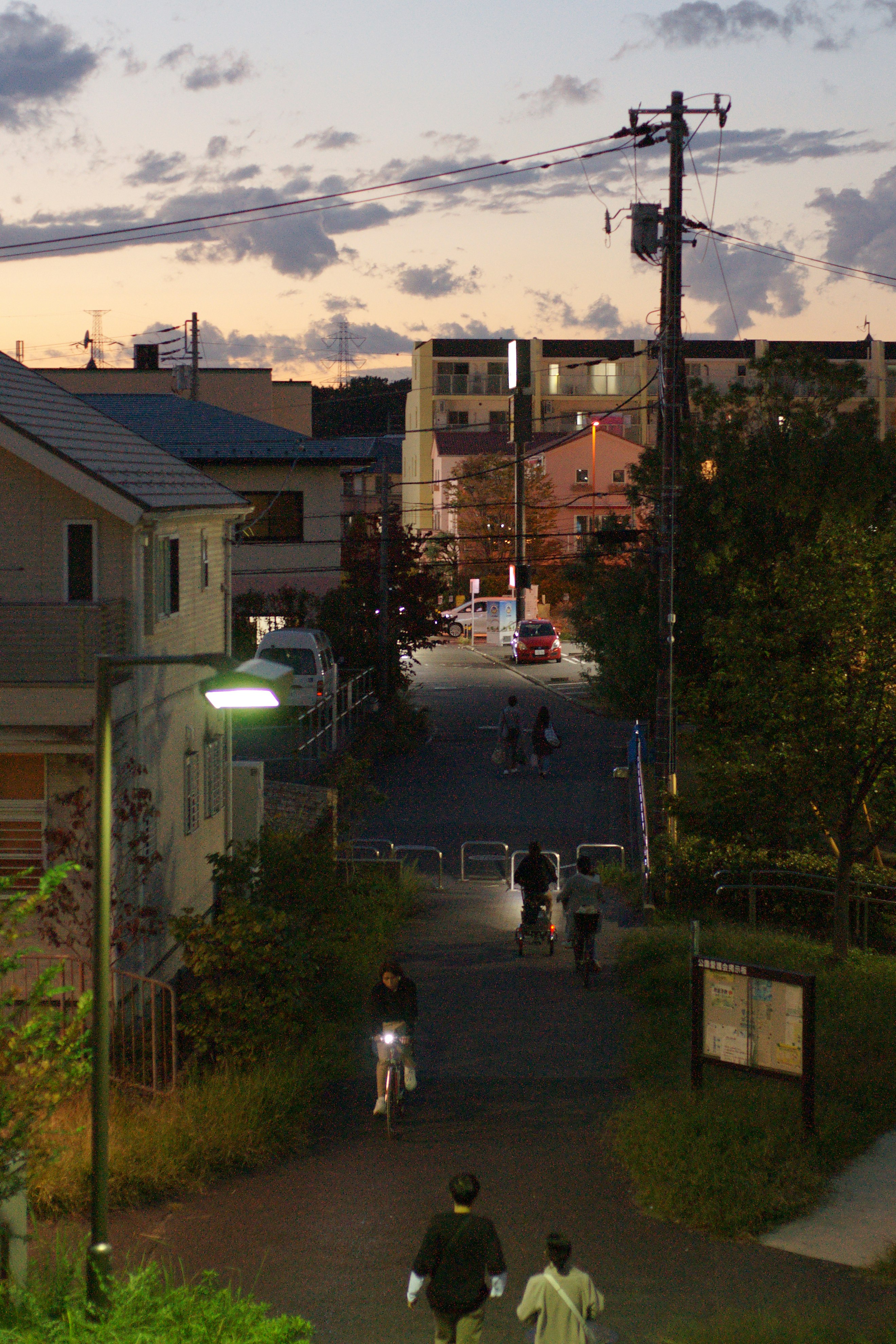 夕暮れの住宅街を歩く人々の路地