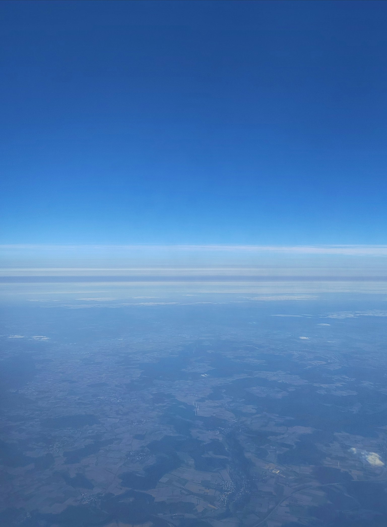 Ein weiter blauer Himmel mit einer Wolkenschicht über der Erde