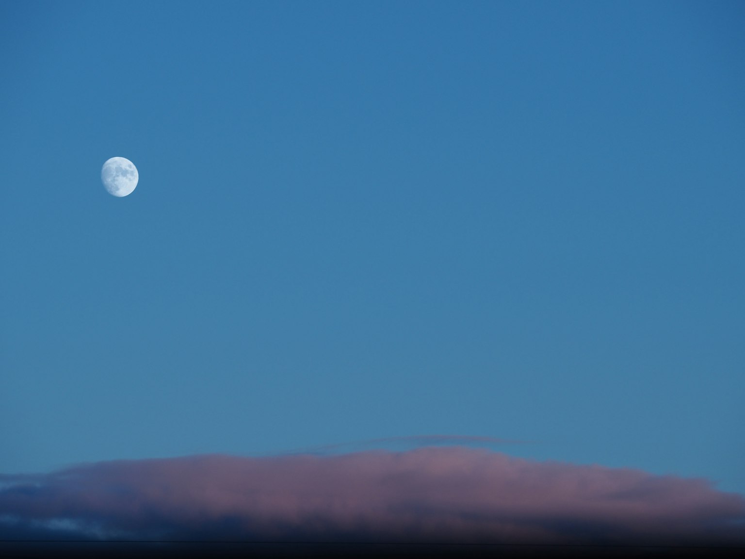 Full moon in a blue sky with soft clouds