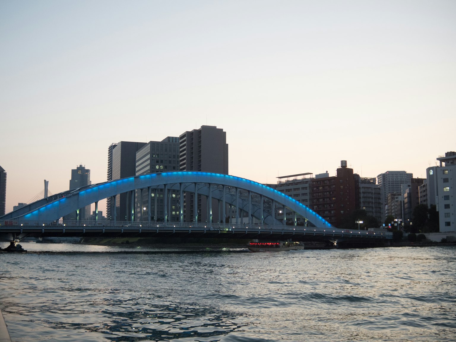 Ponte illuminato di blu al crepuscolo con skyline urbano
