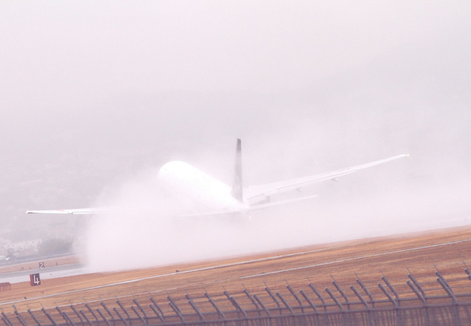 Un avion atterrissant dans le brouillard avec des éclaboussures d'eau à l'arrière
