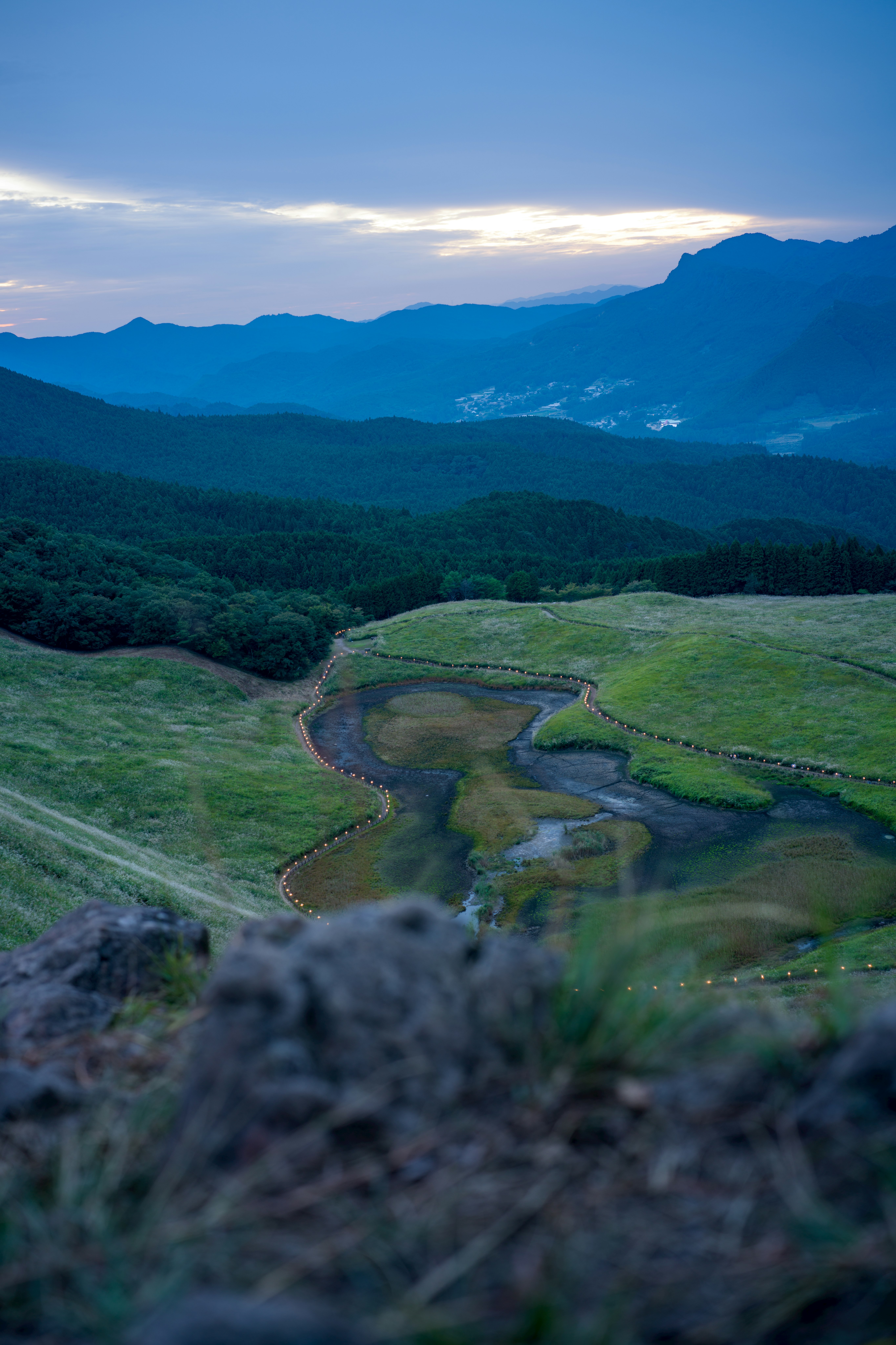 草原の小道が谷へ続く山並みの風景
