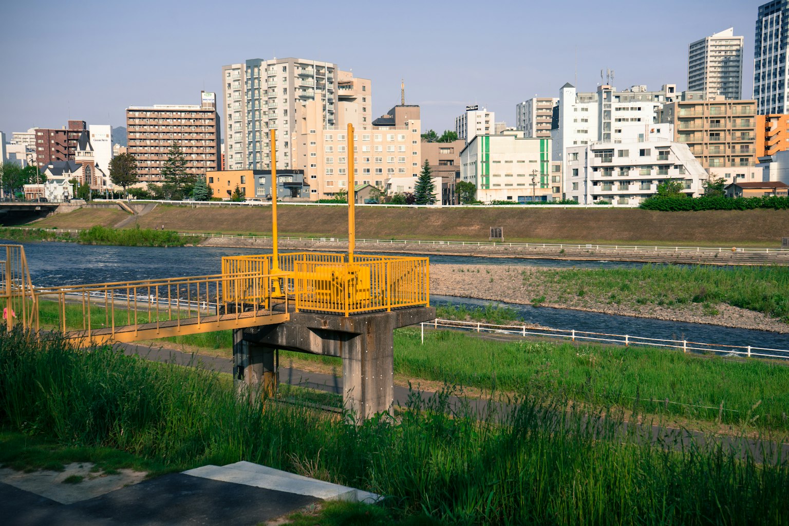 Yellow structure near a river with city skyscrapers in the background