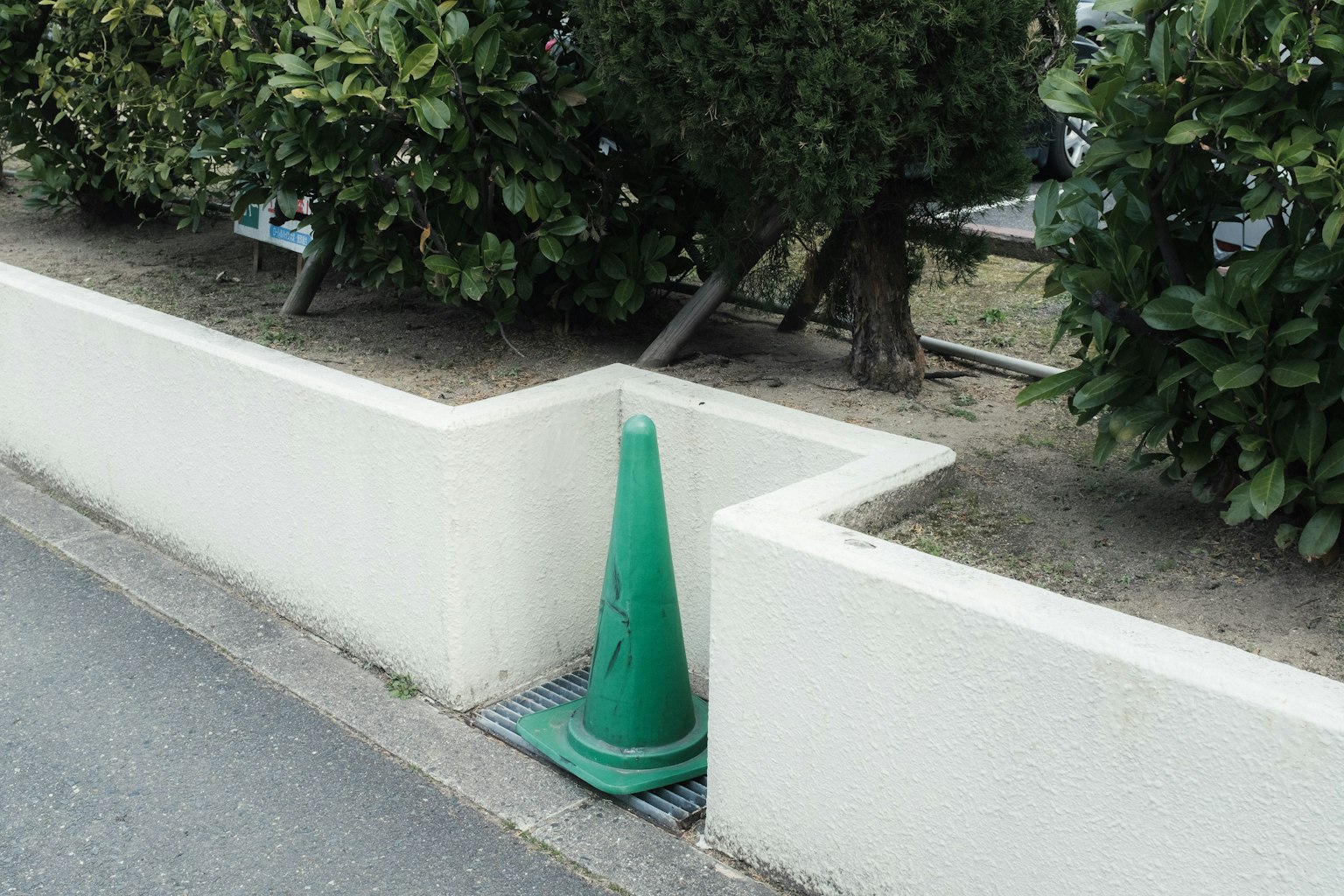 Cono stradale verde posizionato all'angolo di un muro bianco