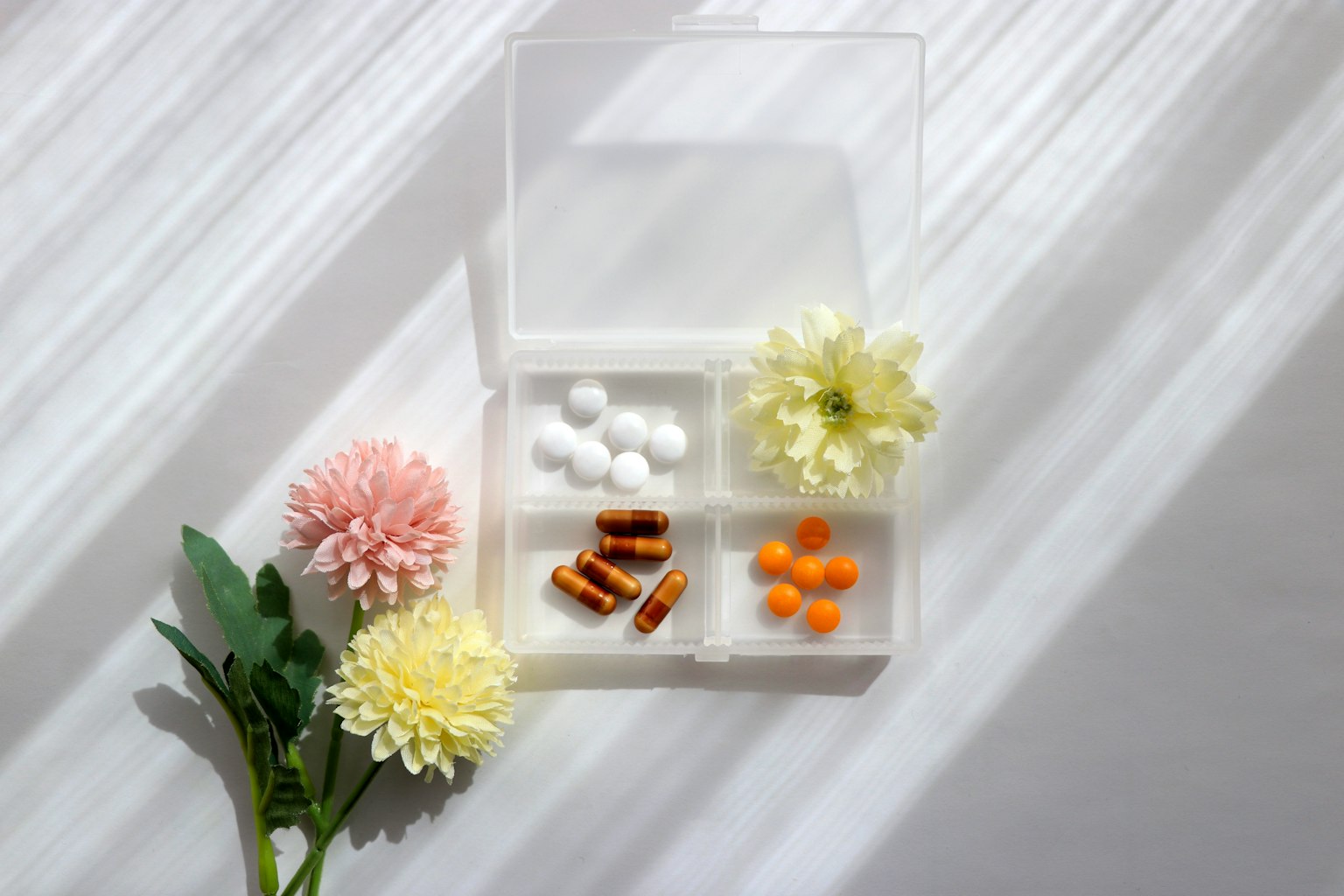Ein einfaches Bild mit bunten Pillen und Blumen auf weißem Hintergrund