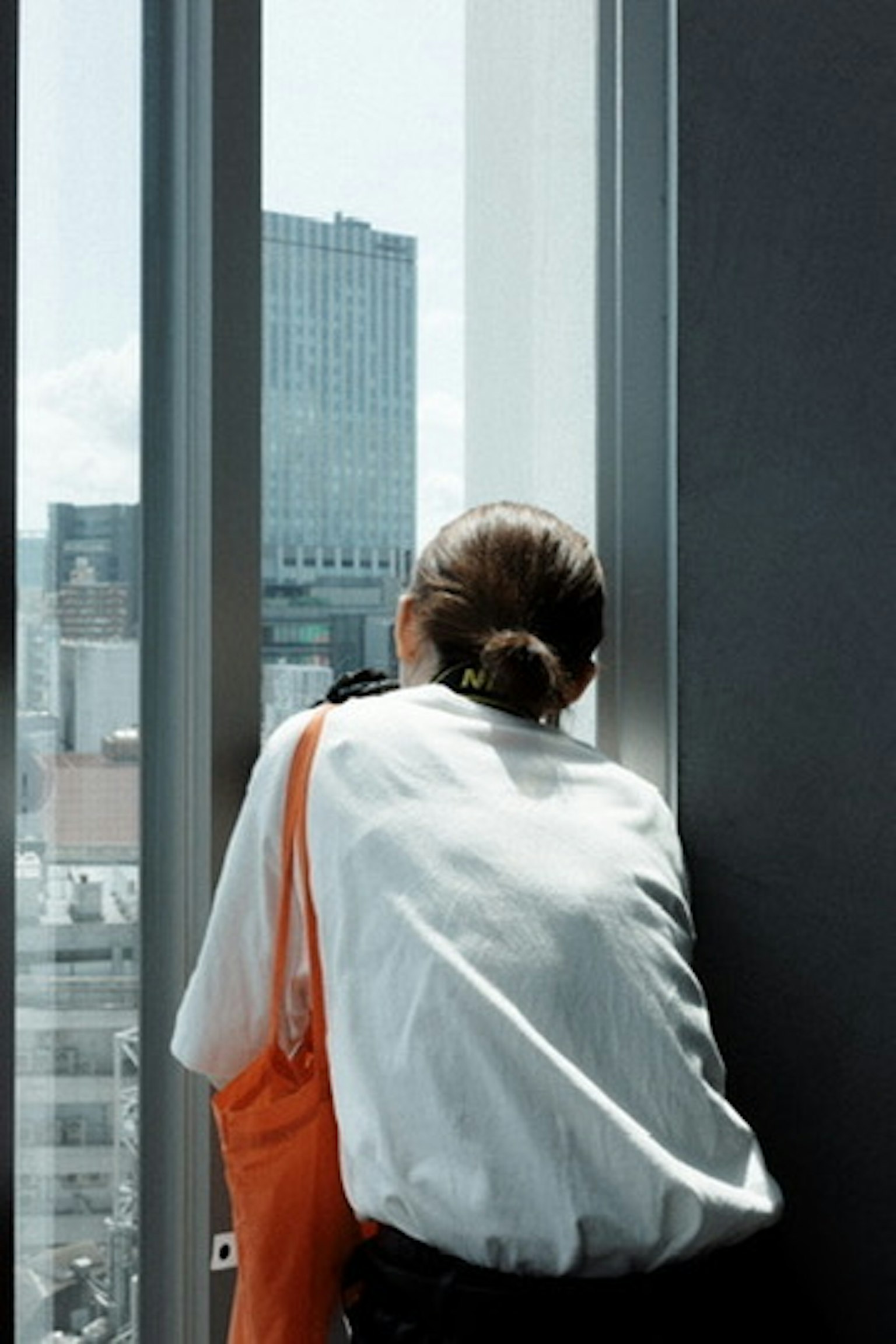 Frau sieht aus dem Fenster mit Stadtlandschaft im Hintergrund