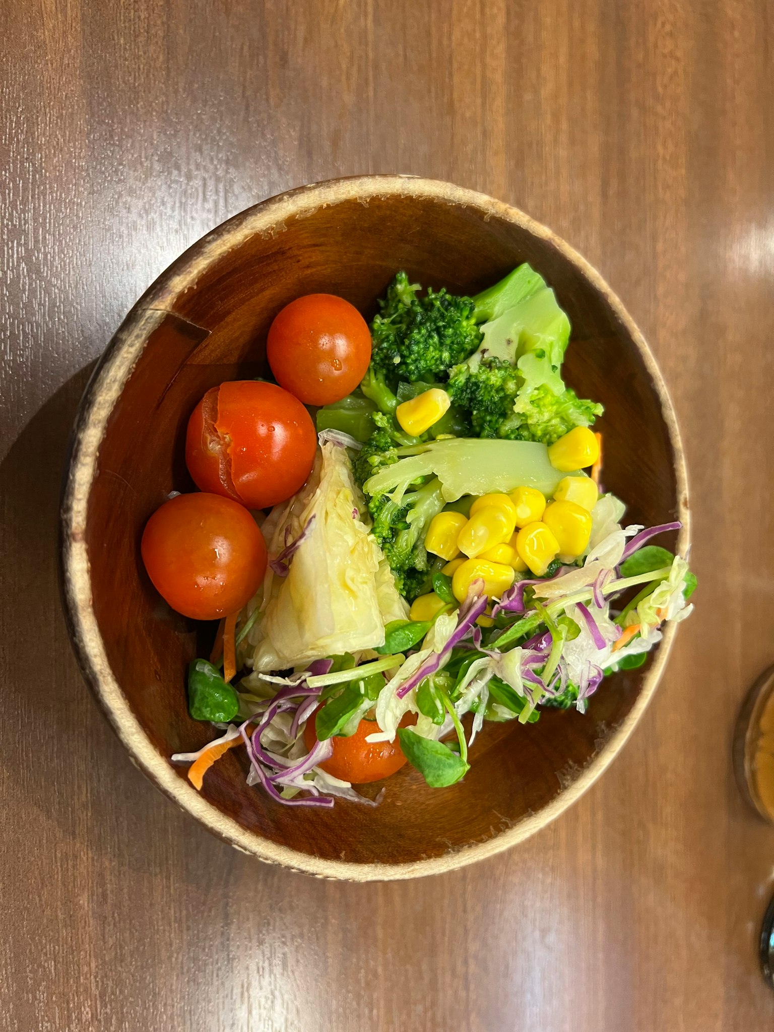 Un tazón de ensalada con tomates frescos, brócoli, maíz y brotes de repollo