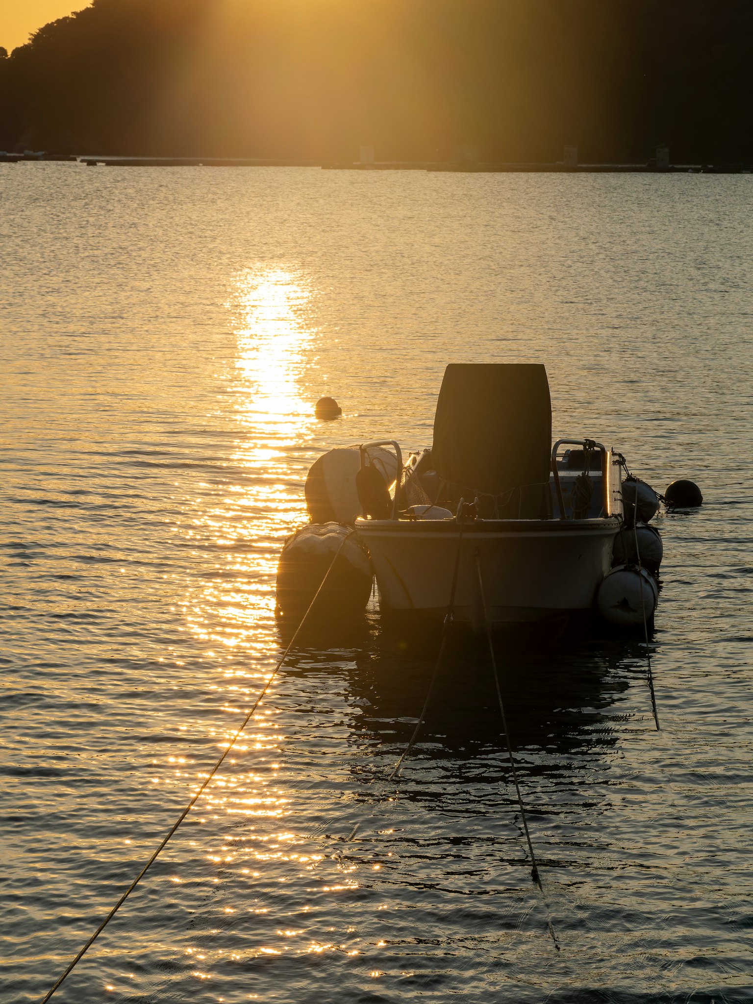Small boat floating on lake water reflecting the sunset