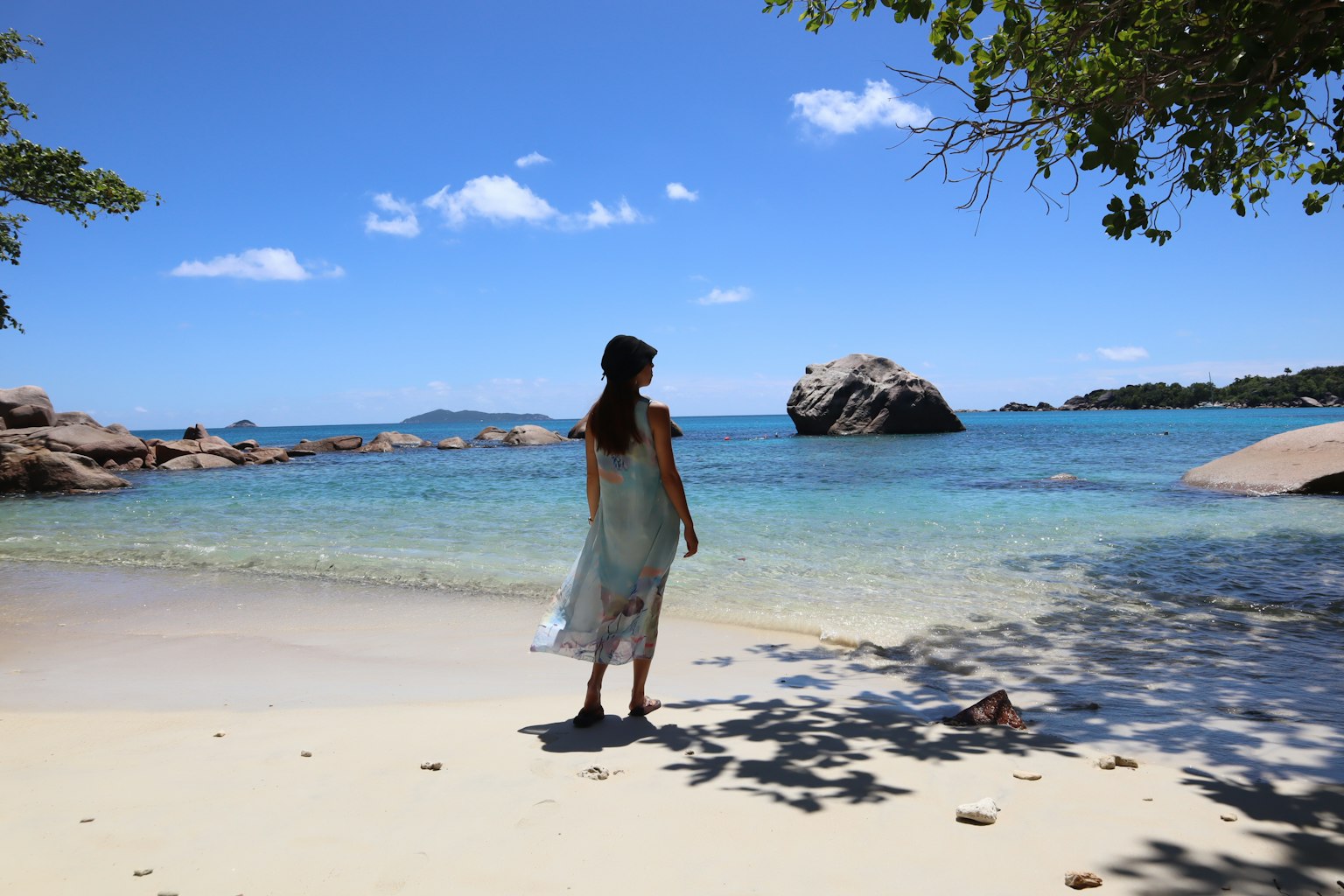 Silhouette d'une femme se tenant sur une plage de sable avec la mer bleue