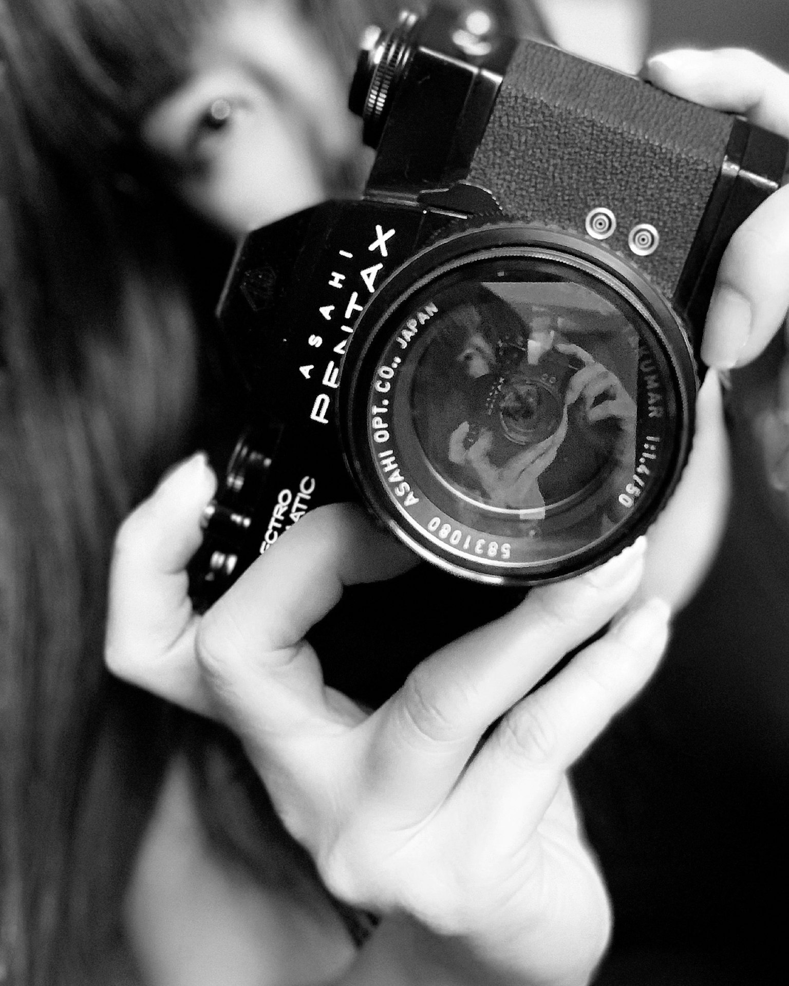 Ảnh đen trắng của một người phụ nữ cầm máy ảnh Pentax
