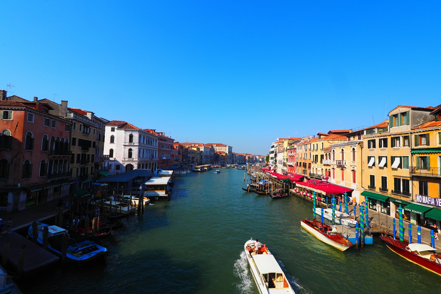 Beautiful view of Venice canal under clear blue sky colorful buildings and boats lining the water