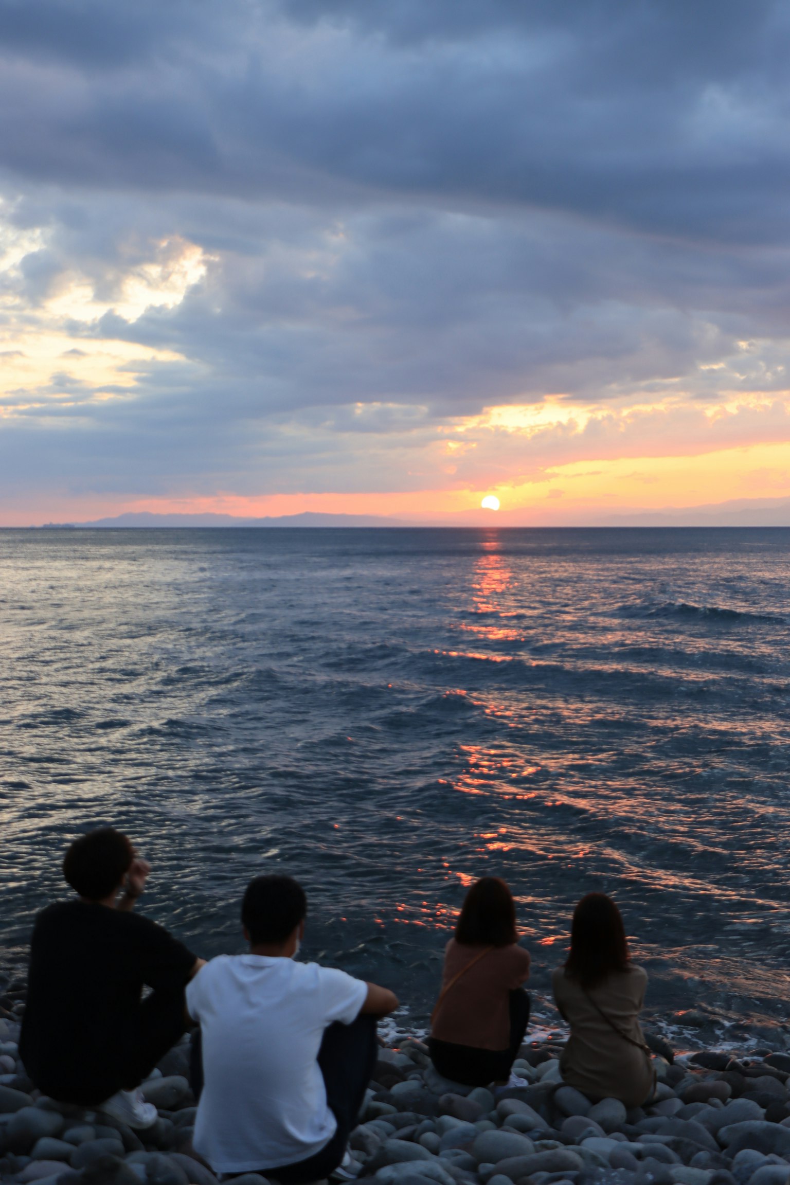 Quattro amici che guardano il tramonto al mare