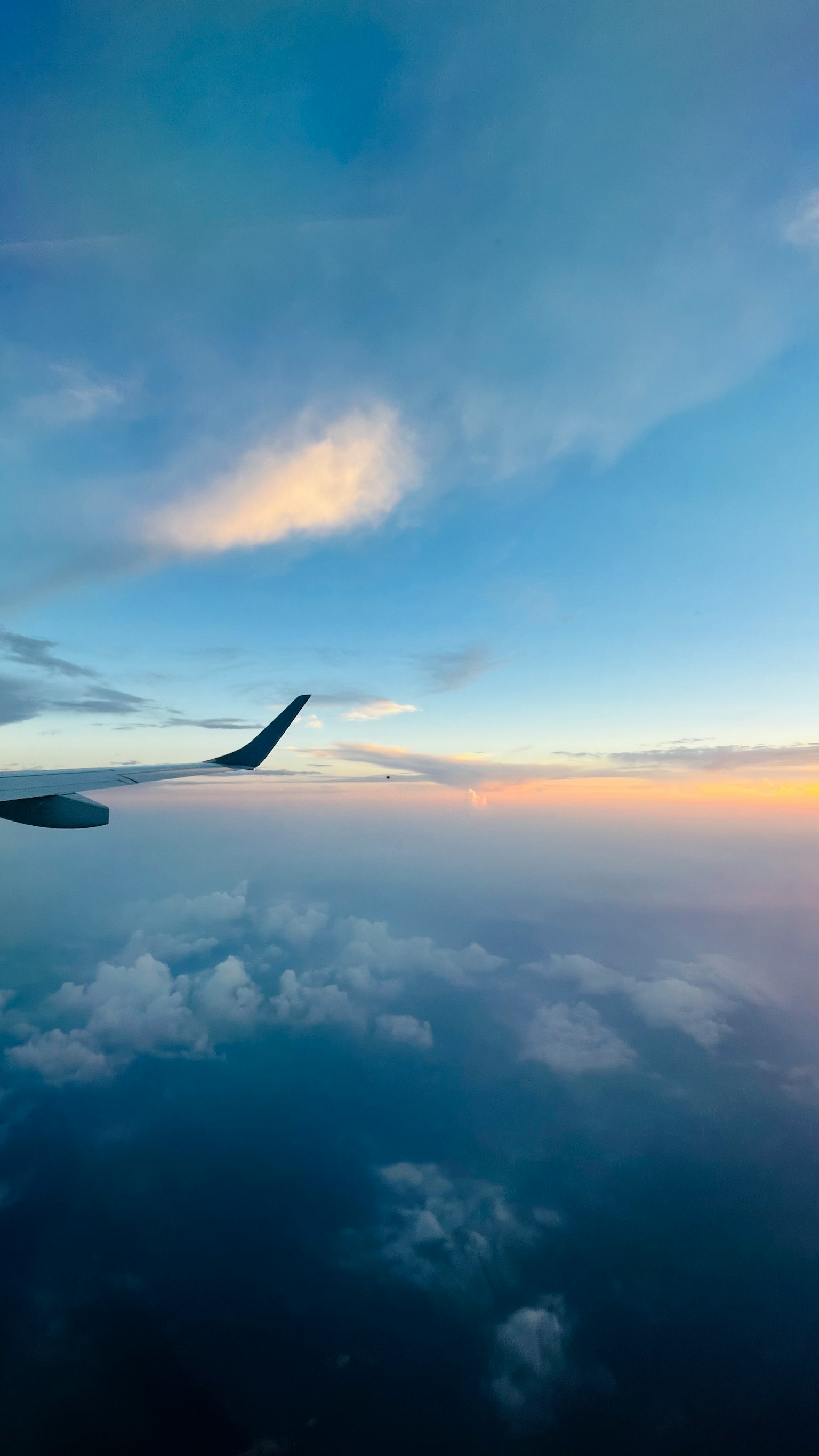 Flugzeugflügel vor einem bunten Himmel