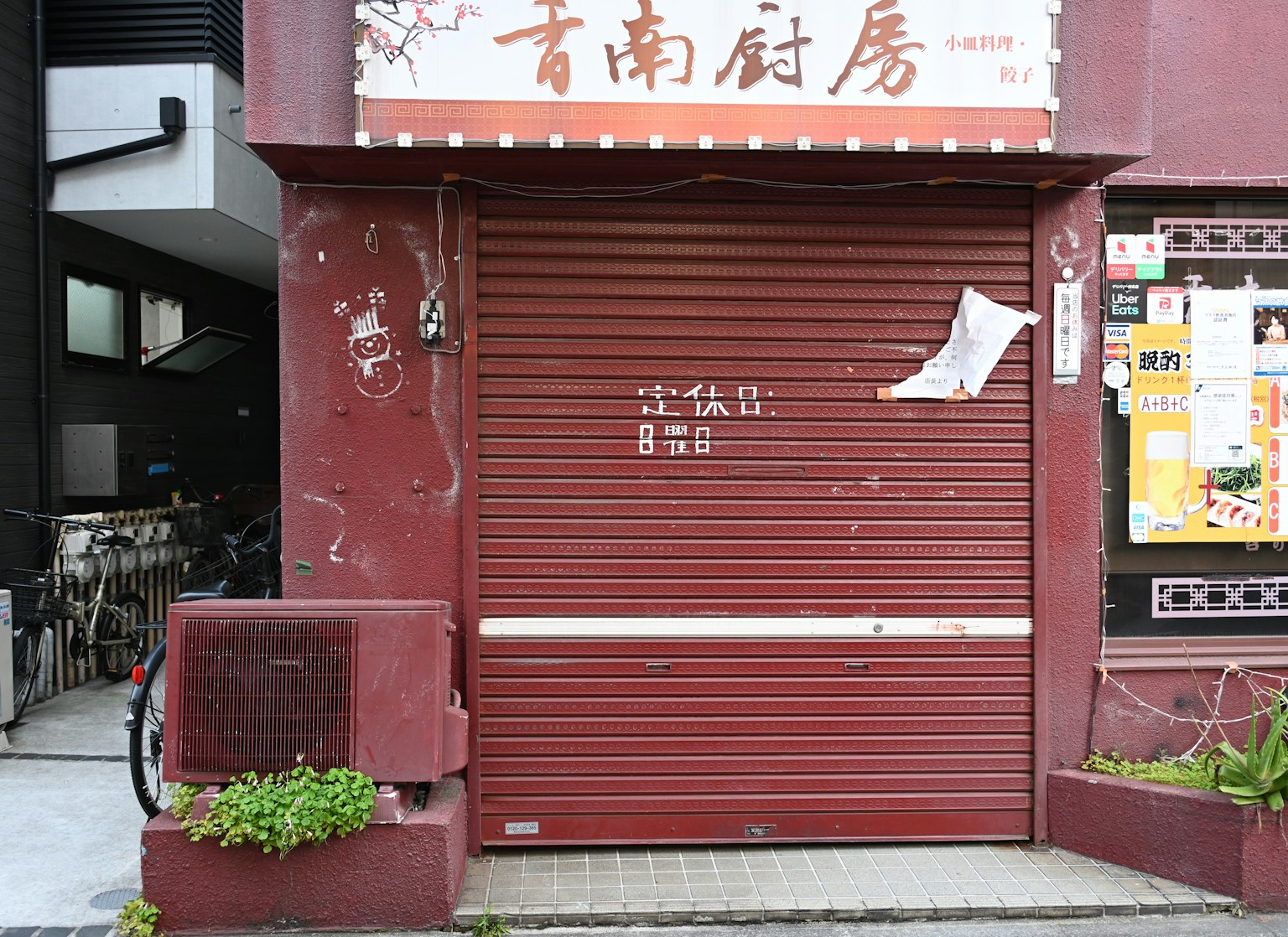 ประตูม้วนสีน้ำตาลแดงของร้านค้าที่ปิดอยู่ใกล้จักรยาน