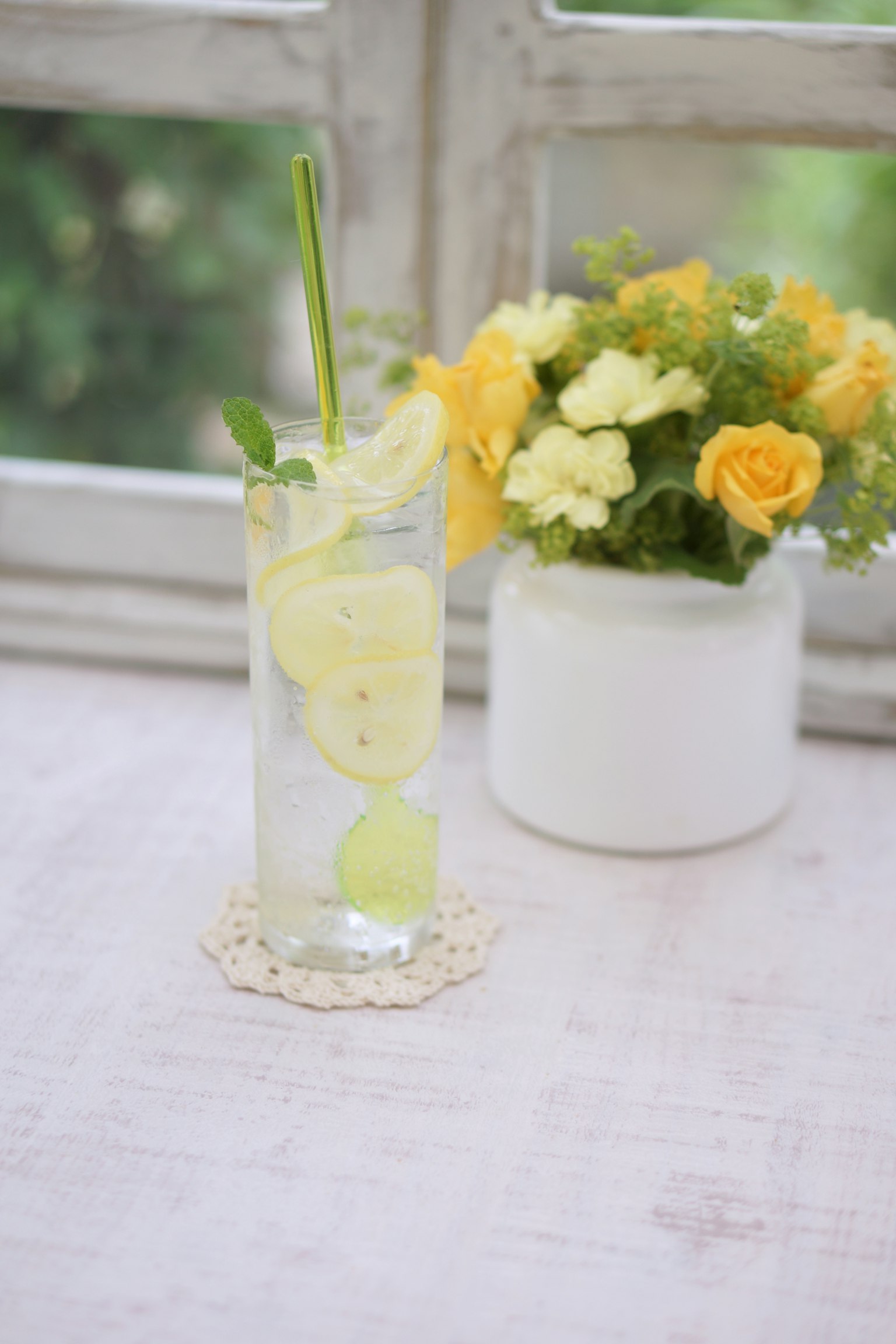 Đồ uống chanh mát lạnh với bạc hà bên cạnh bình hoa vàng