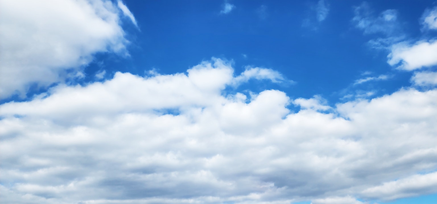 Eine Landschaft mit blauem Himmel und fluffigen weißen Wolken