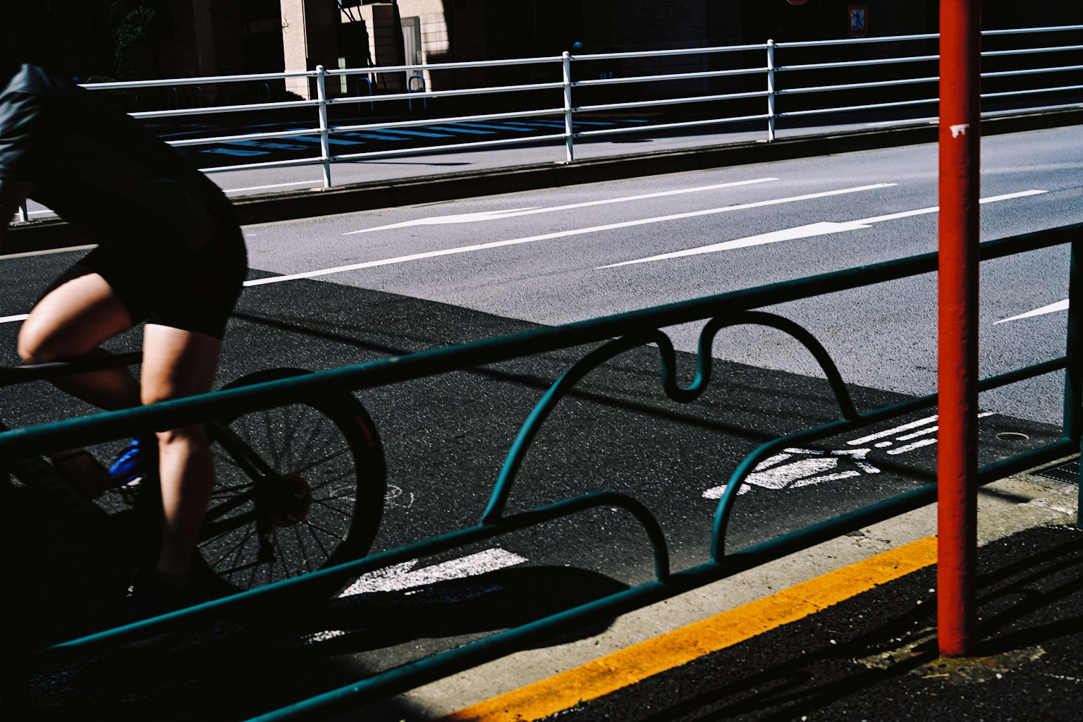 自転車に乗る人の足と自転車の一部が見える街の風景