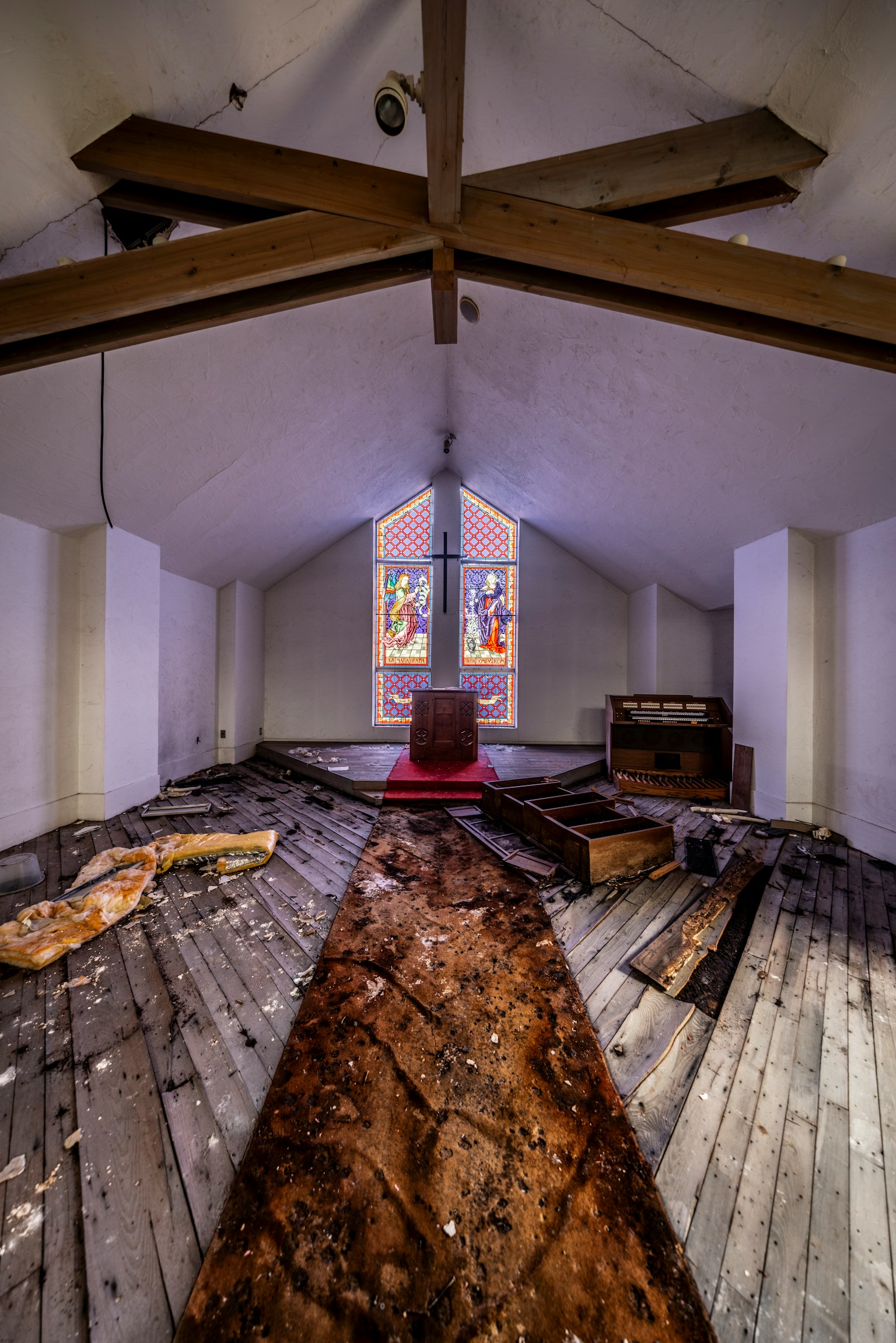 Intérieur d'une église abandonnée avec des poutres en bois et un sol lumineux à travers une fenêtre
