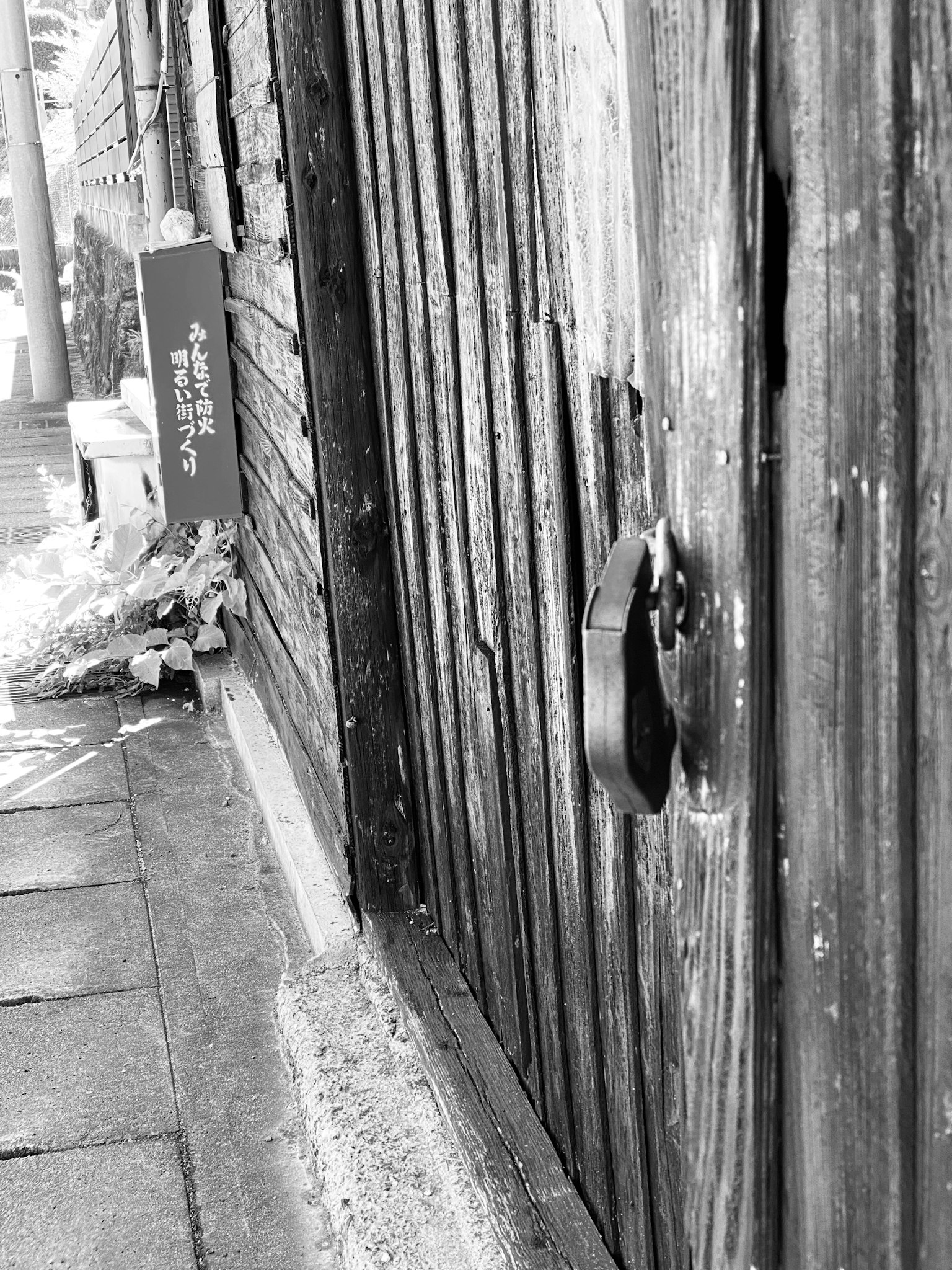 Primo piano di una vecchia porta di legno con una serratura e un sentiero in ciottoli