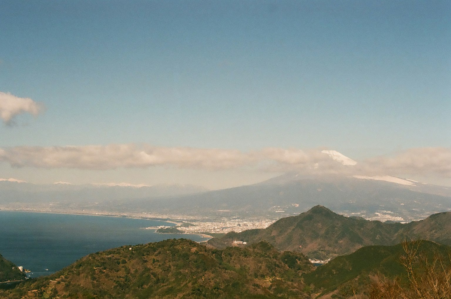 Scenic view of mountains and ocean under a blue sky with clouds