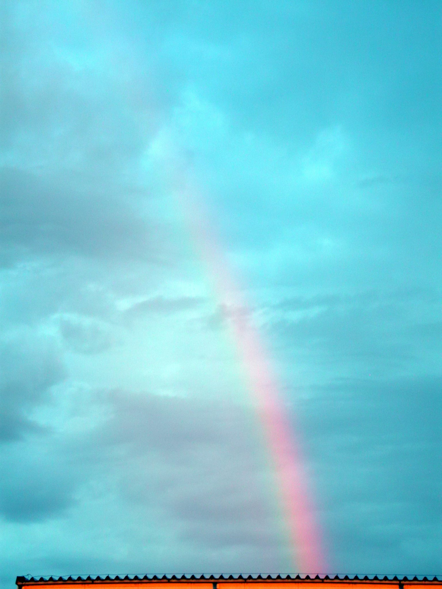 Arcobaleno che si estende su un cielo blu con nuvole