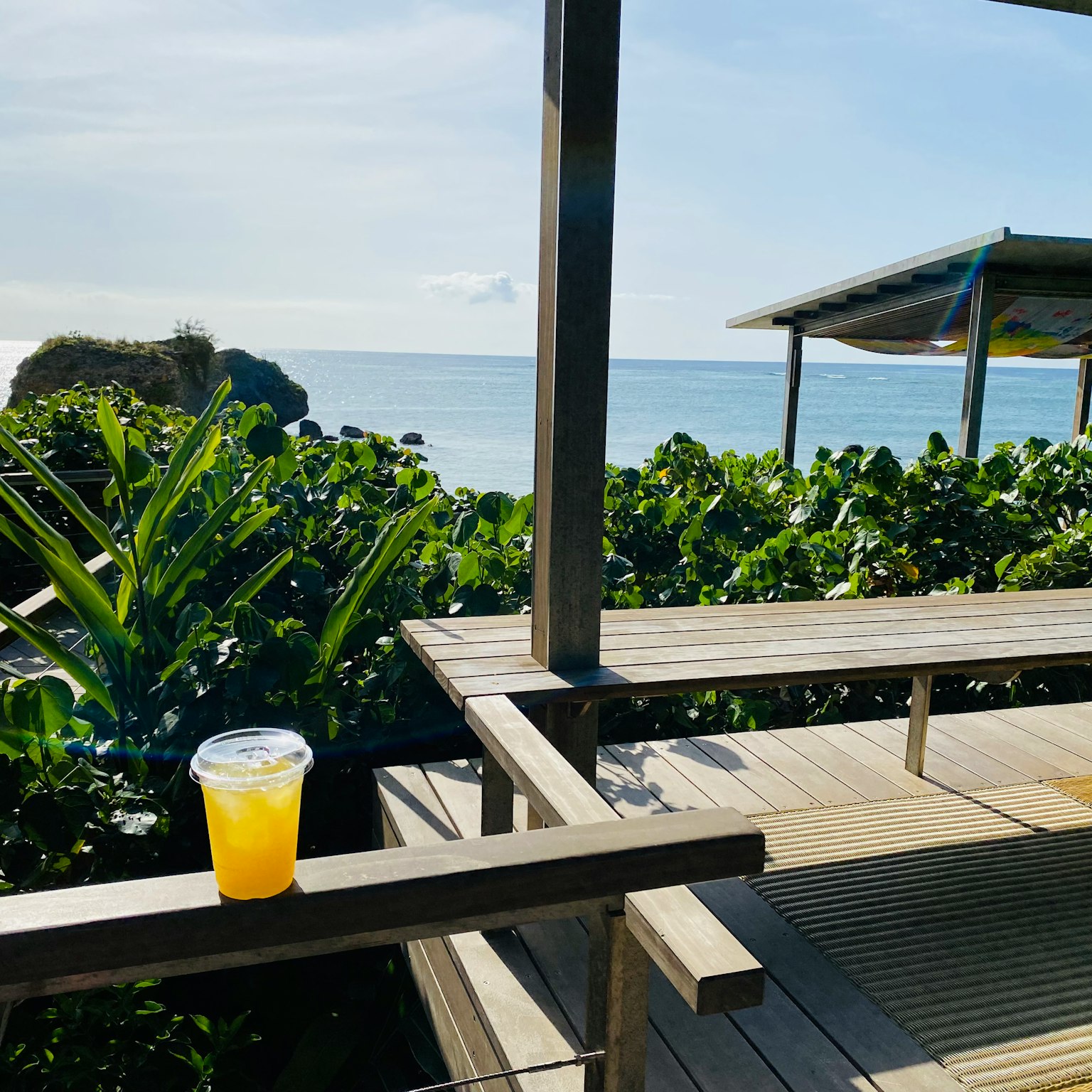 Tazza di succo d'arancia su una terrazza di legno con vista sul mare