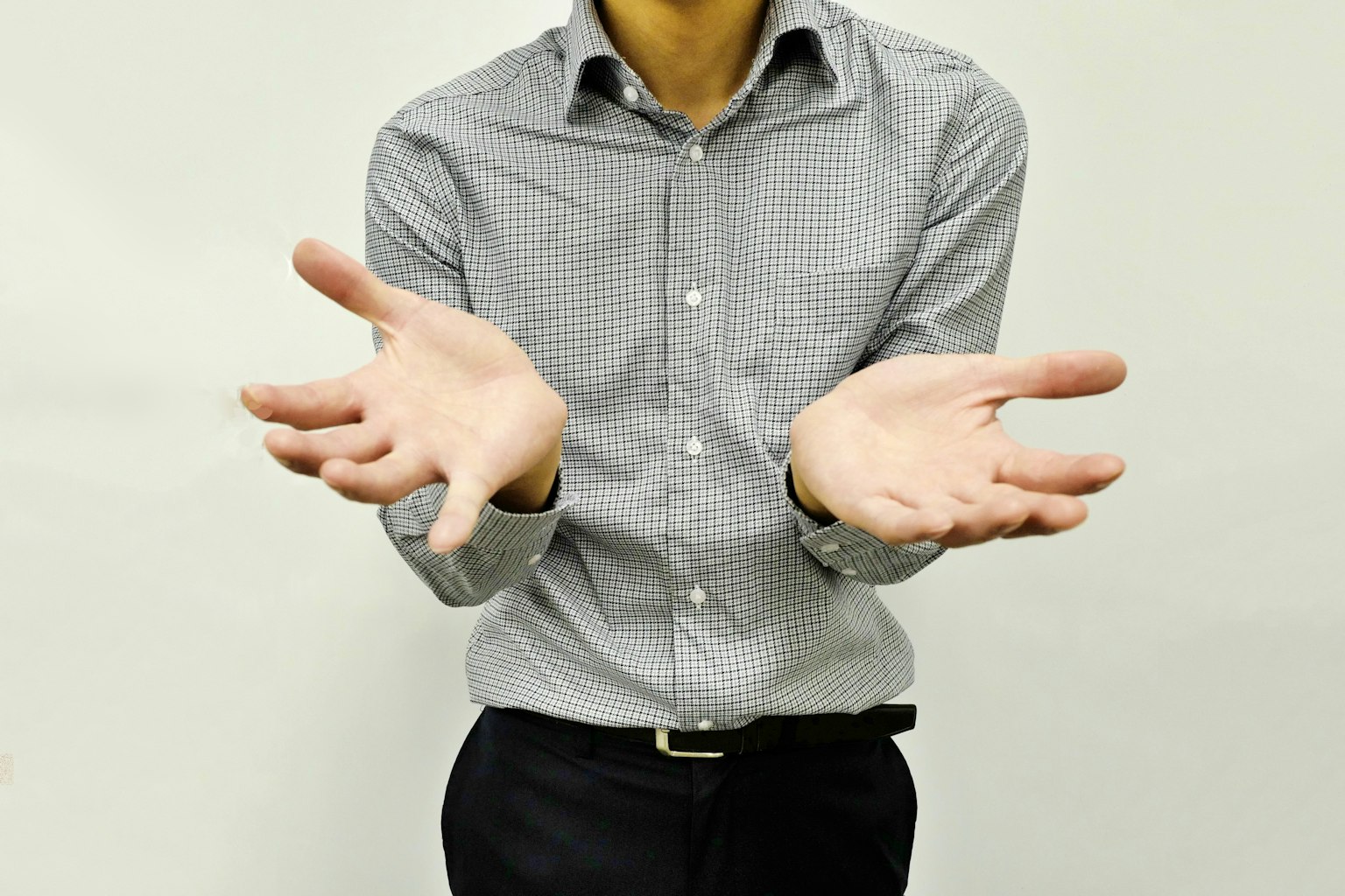 Một người đàn ông với hai tay giang ra mặc áo sơ mi xám