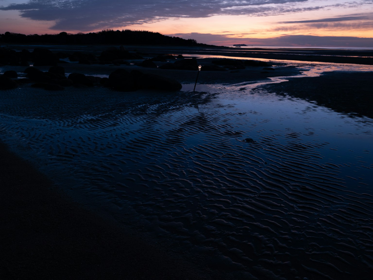 Scena serena di estuario illuminata dai colori del tramonto riflessi sull'acqua