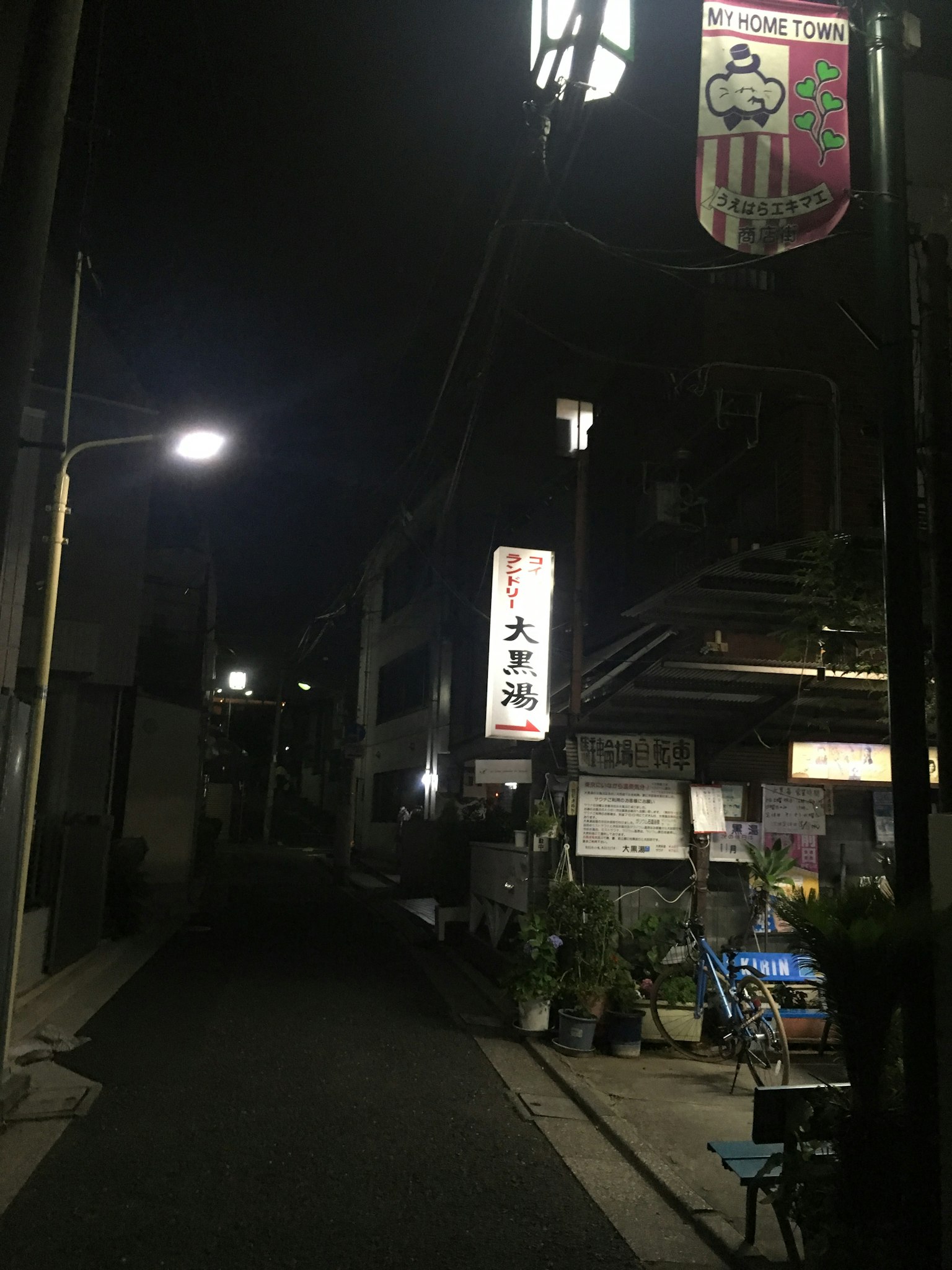 Ruelle étroite la nuit avec des panneaux et des lampadaires