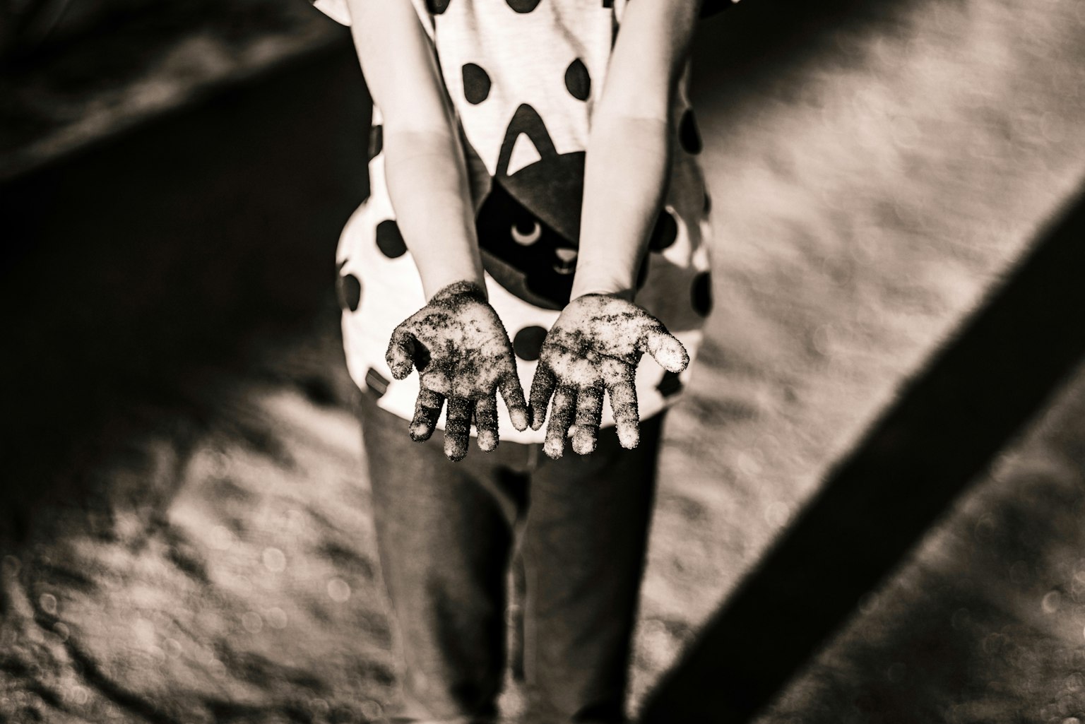 Black and white photo of a child wearing a polka dot shirt holding out hands