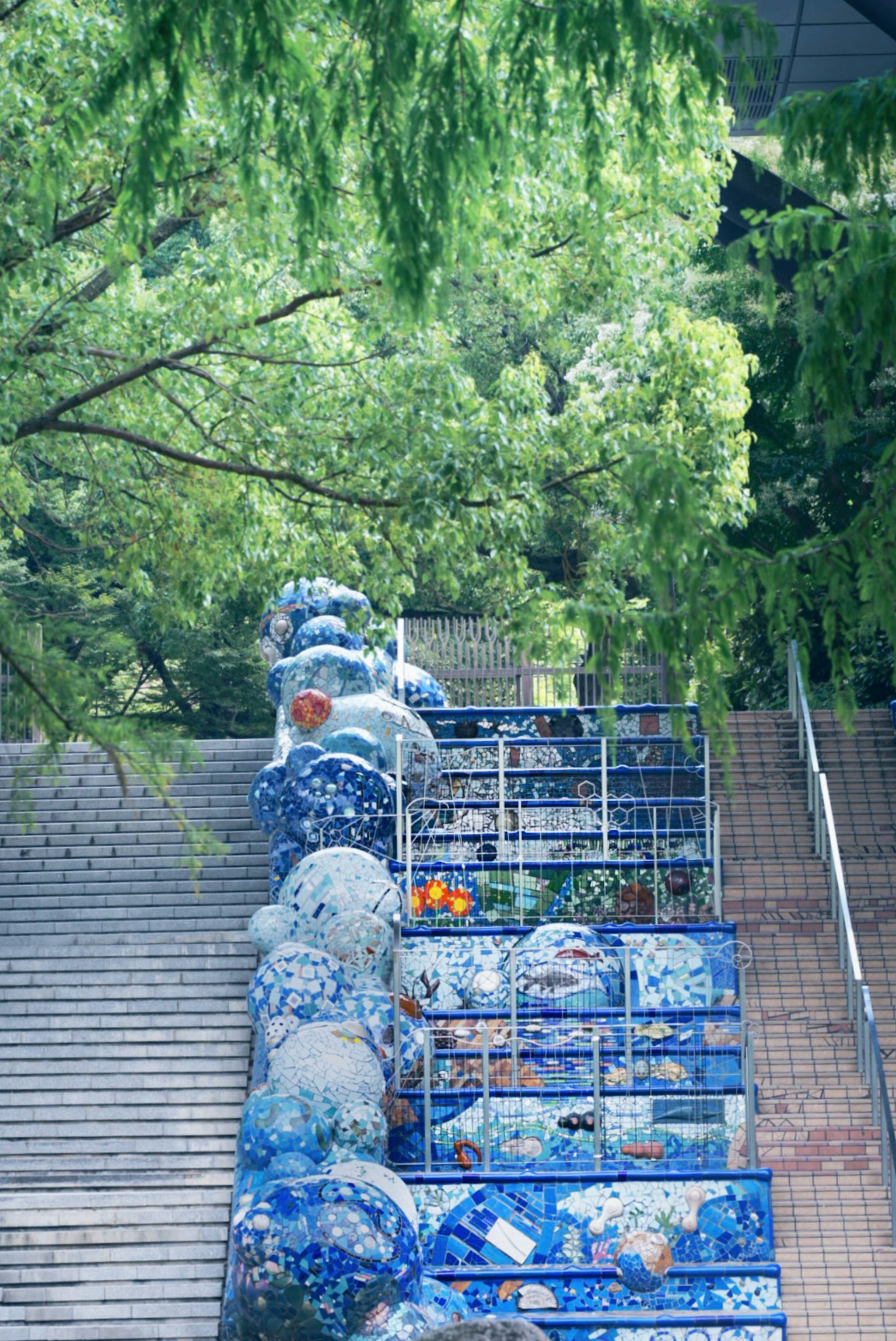 青い陶器のオブジェが並ぶ階段の風景 緑の木々に囲まれた静かな場所