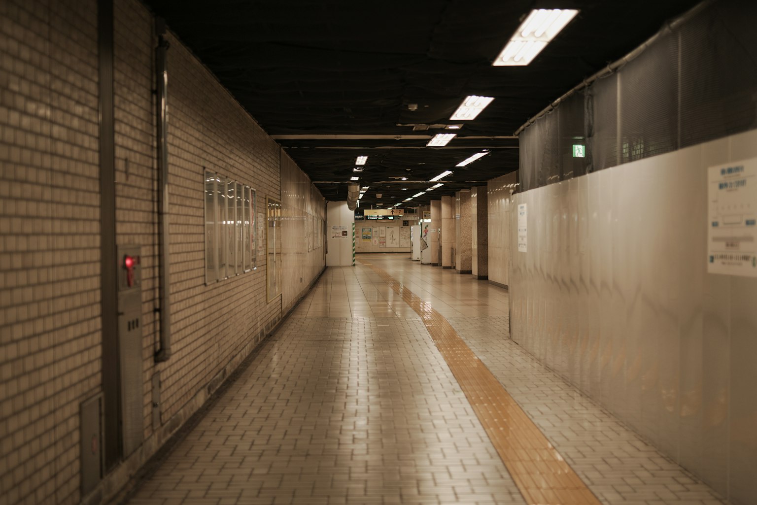 Long corridor in an underground passage featuring bright lighting and tiled floor
