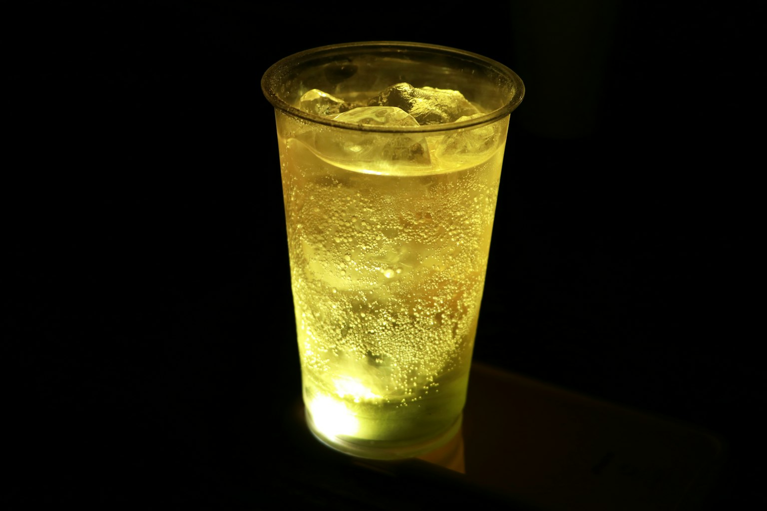 暗背景下發光的黃色飲料杯